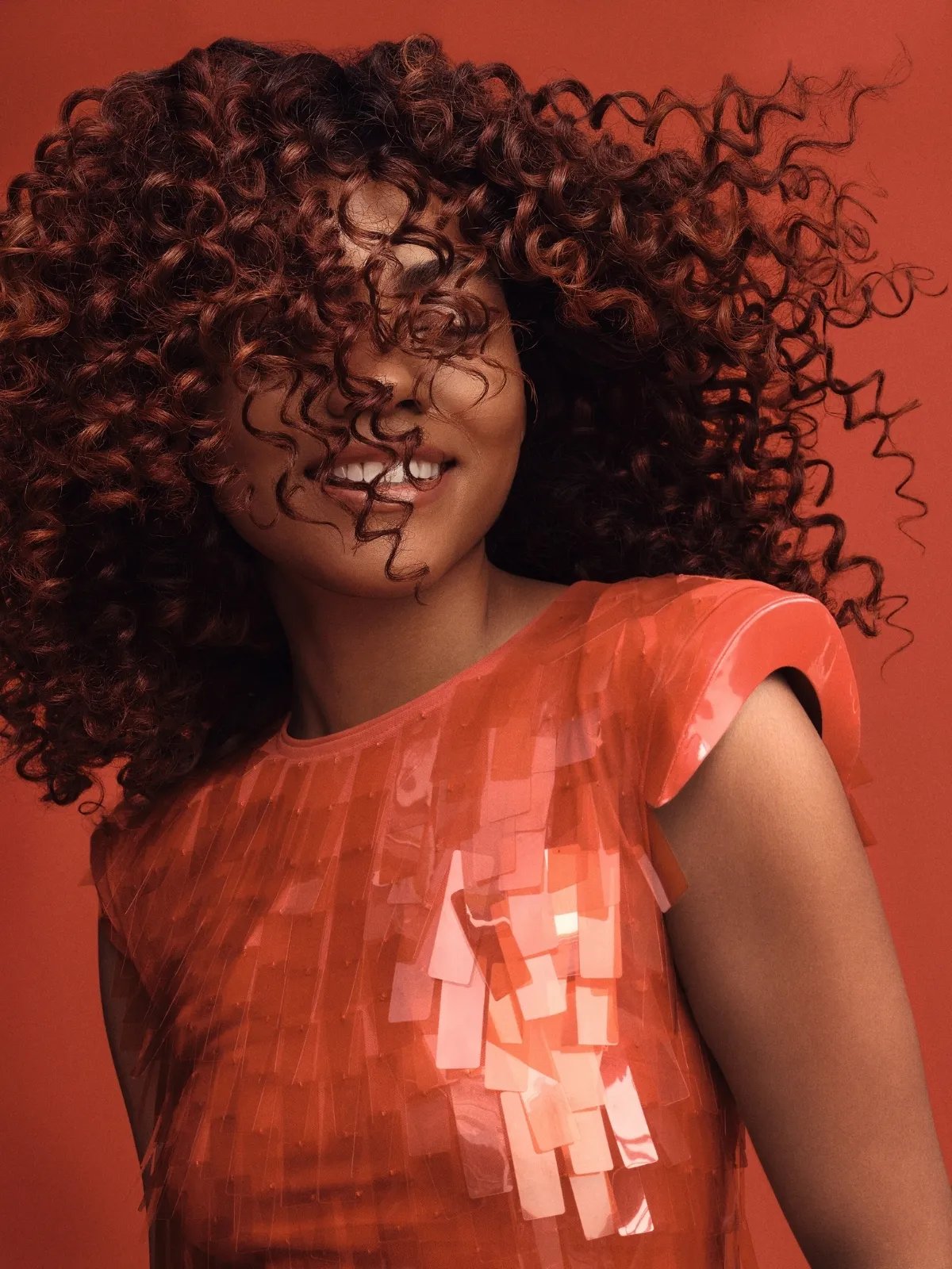 Model swishes their glossy, healthy, curly, brown hair.