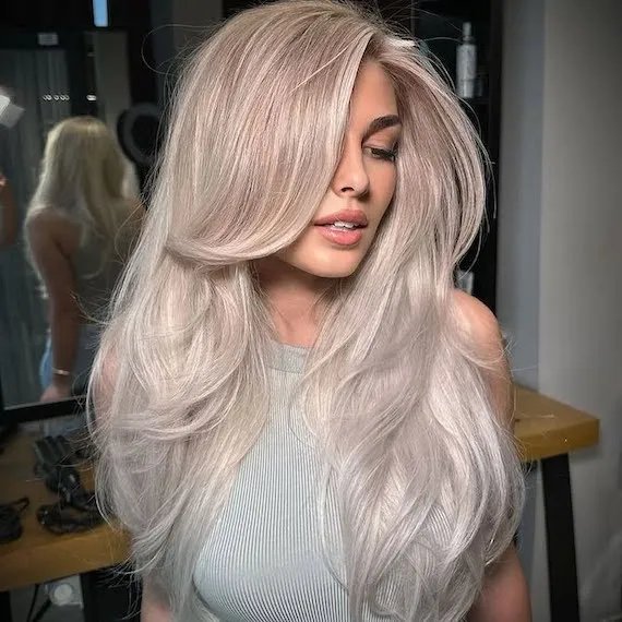 Model with long, icy platinum blonde hair styled in a bouncy blow-dry.