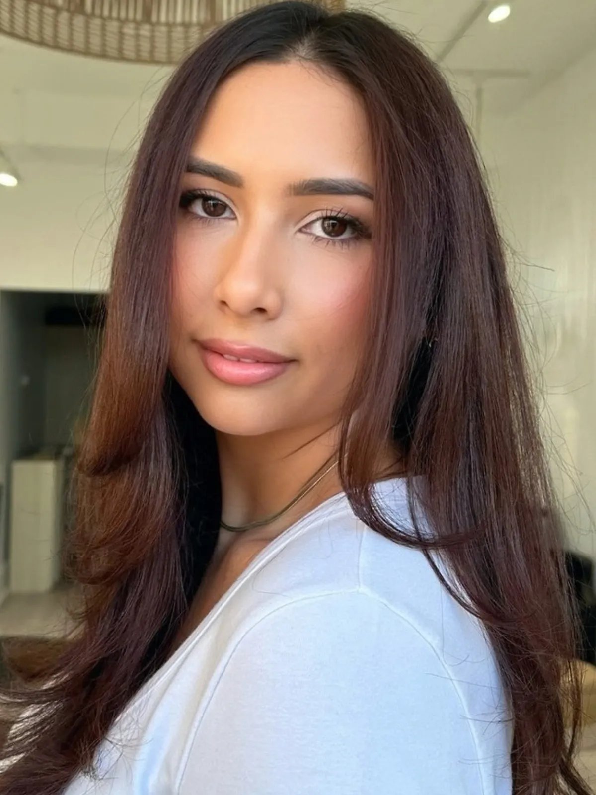 Model with long, brown hair, featuring sweeps of maroon red.