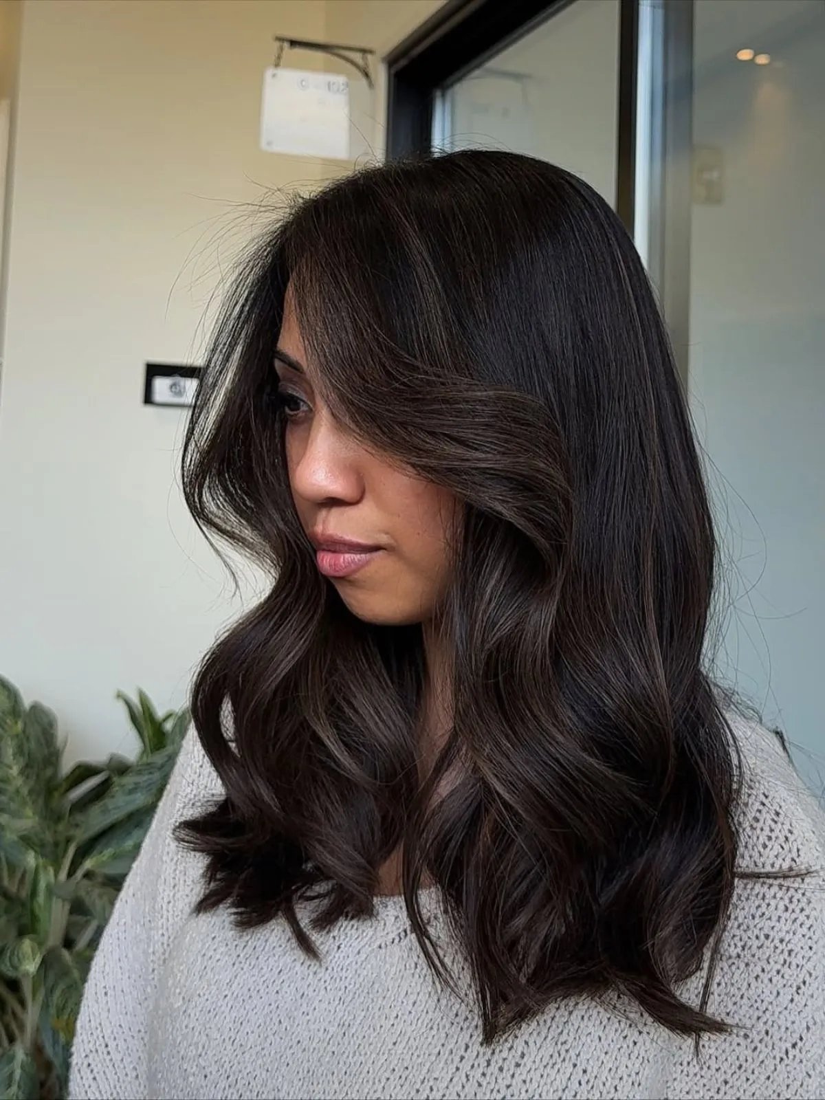Model with long, loosely curled, espresso brunette hair, featuring subtle highlights. 