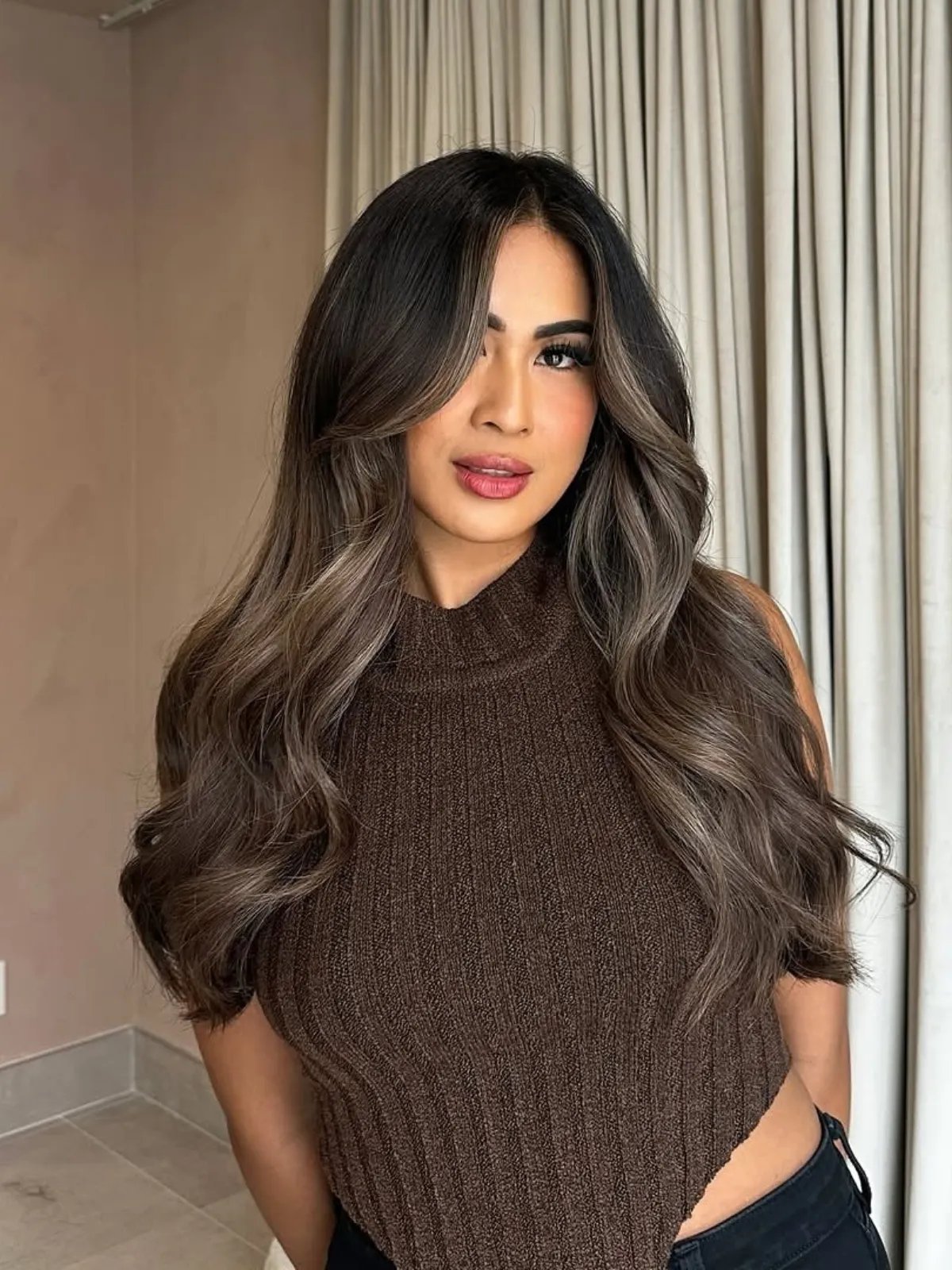 Model with dark brown hair and subtle ash blonde highlights framing her face.