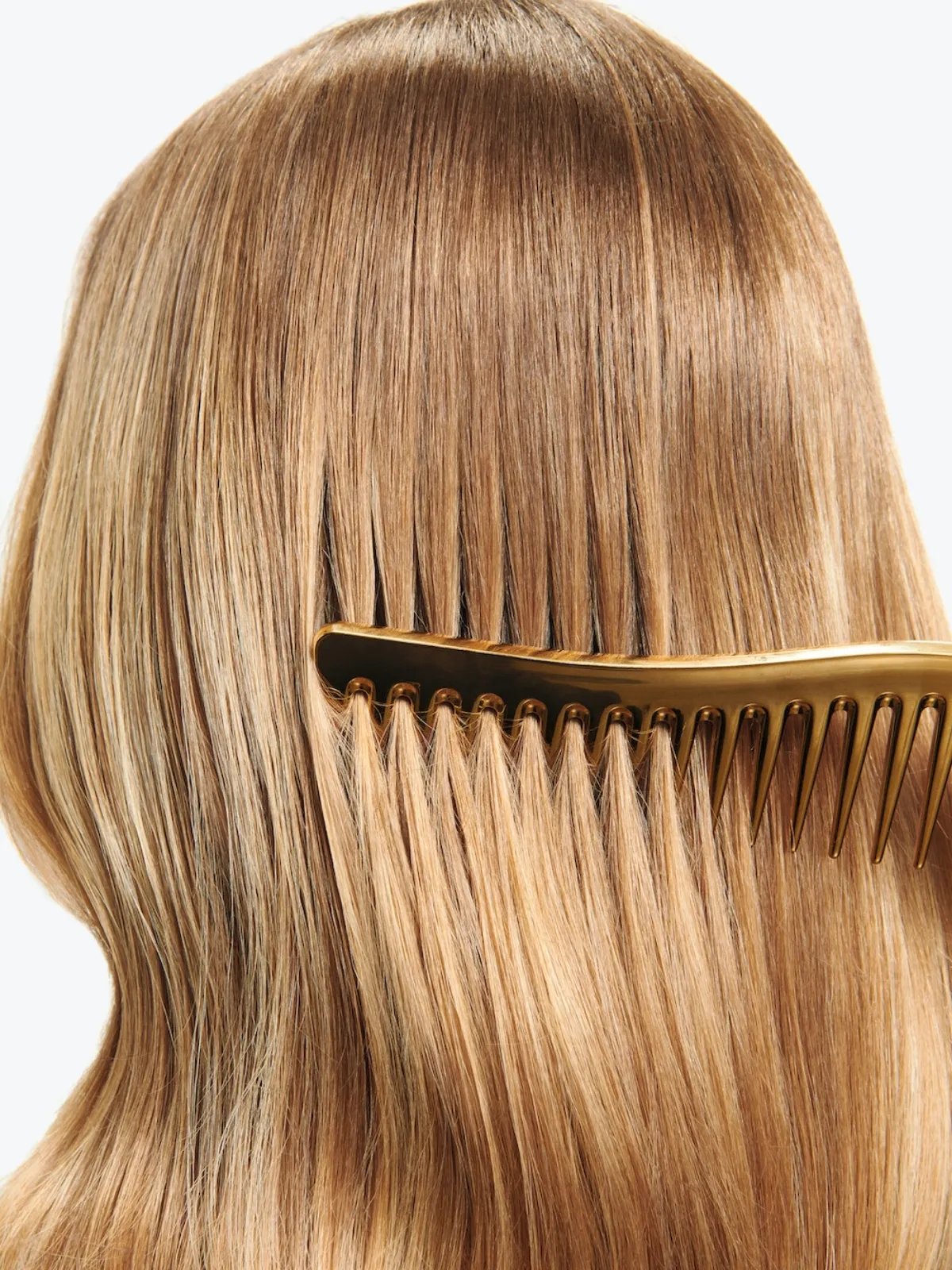 Golden comb glides through model’s golden blonde hair.