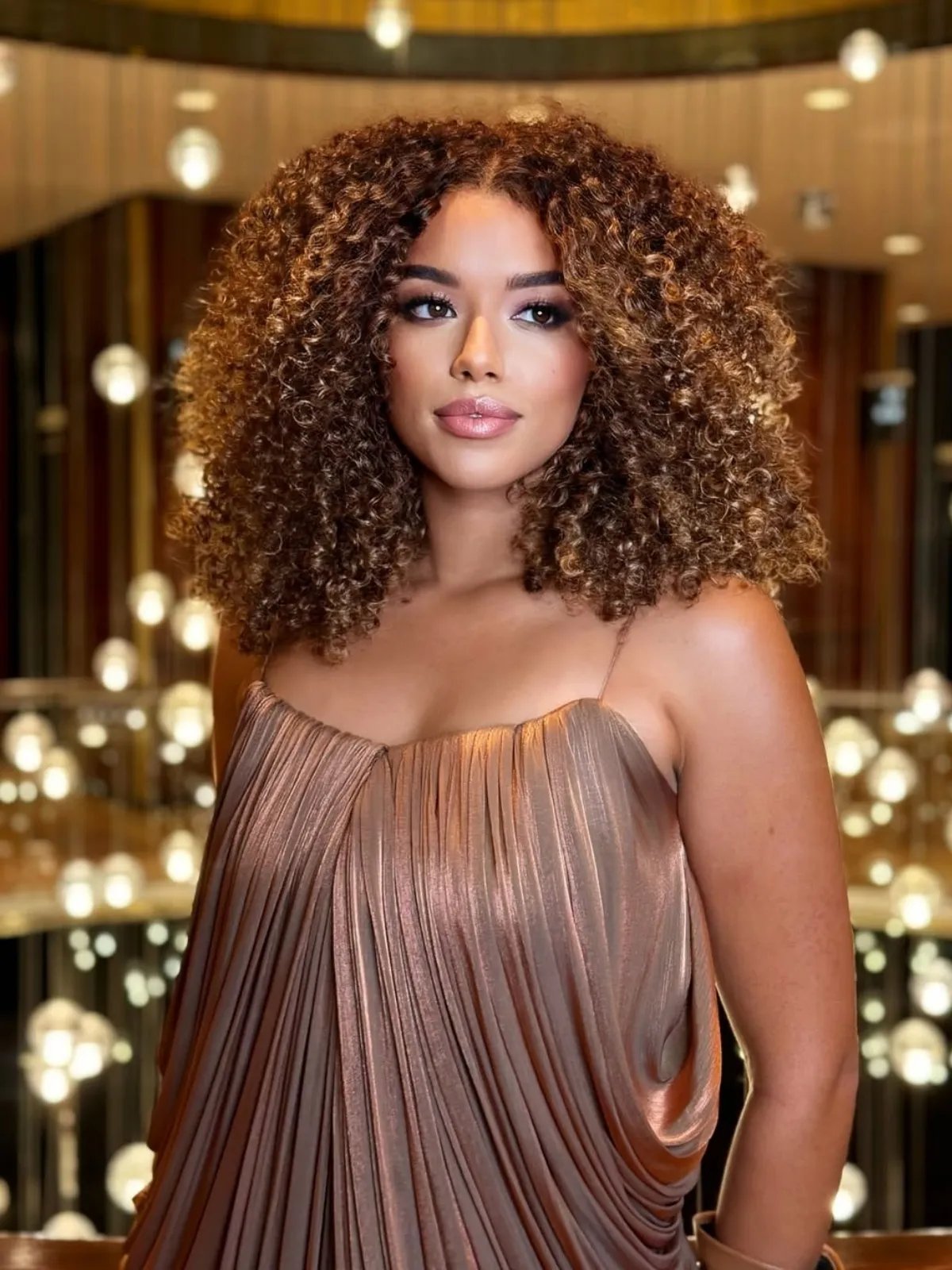 Model with curly, glossy, dark golden blonde hair.