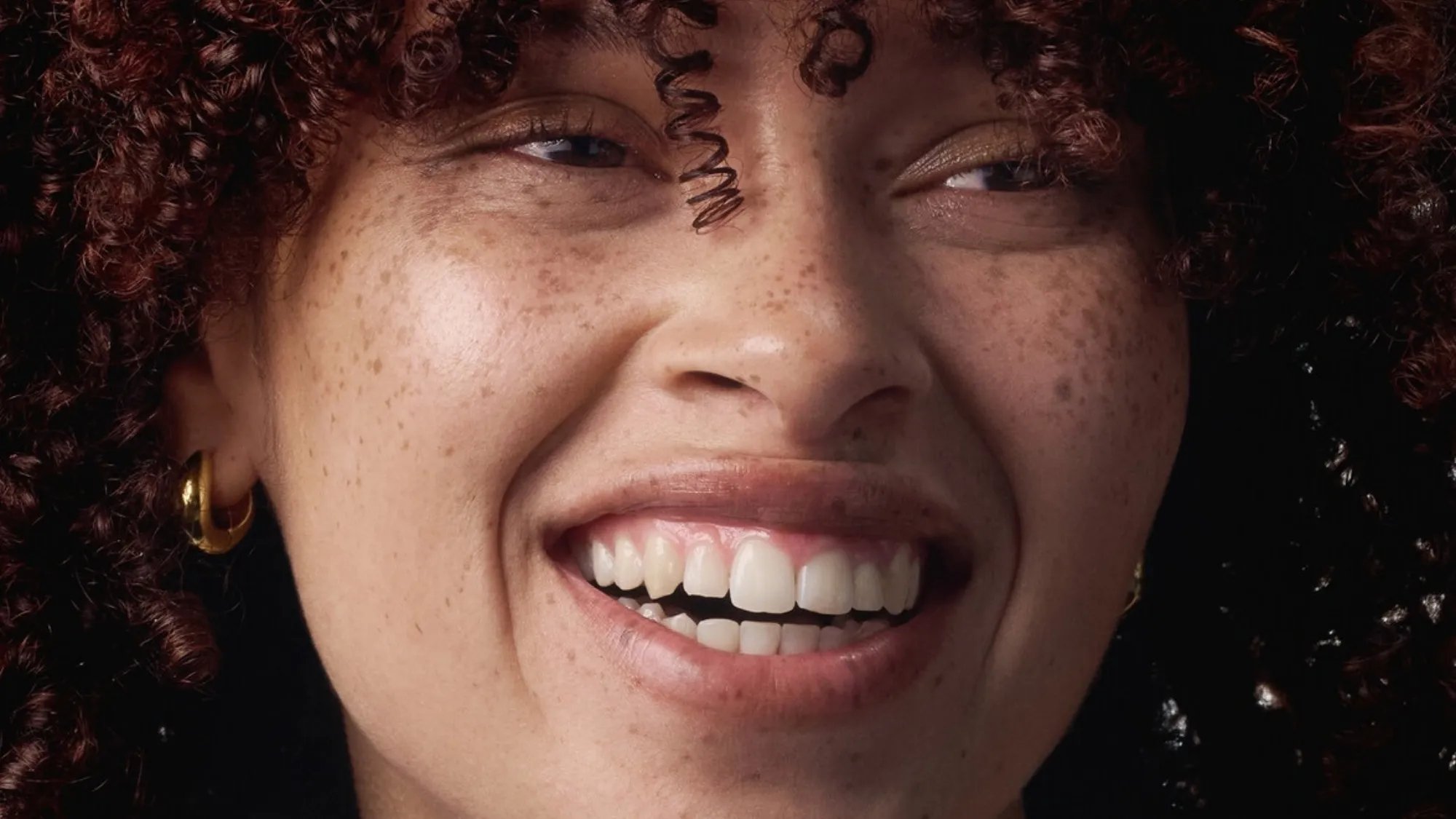 Model with beautifully glossy, dark mahogany red curls.