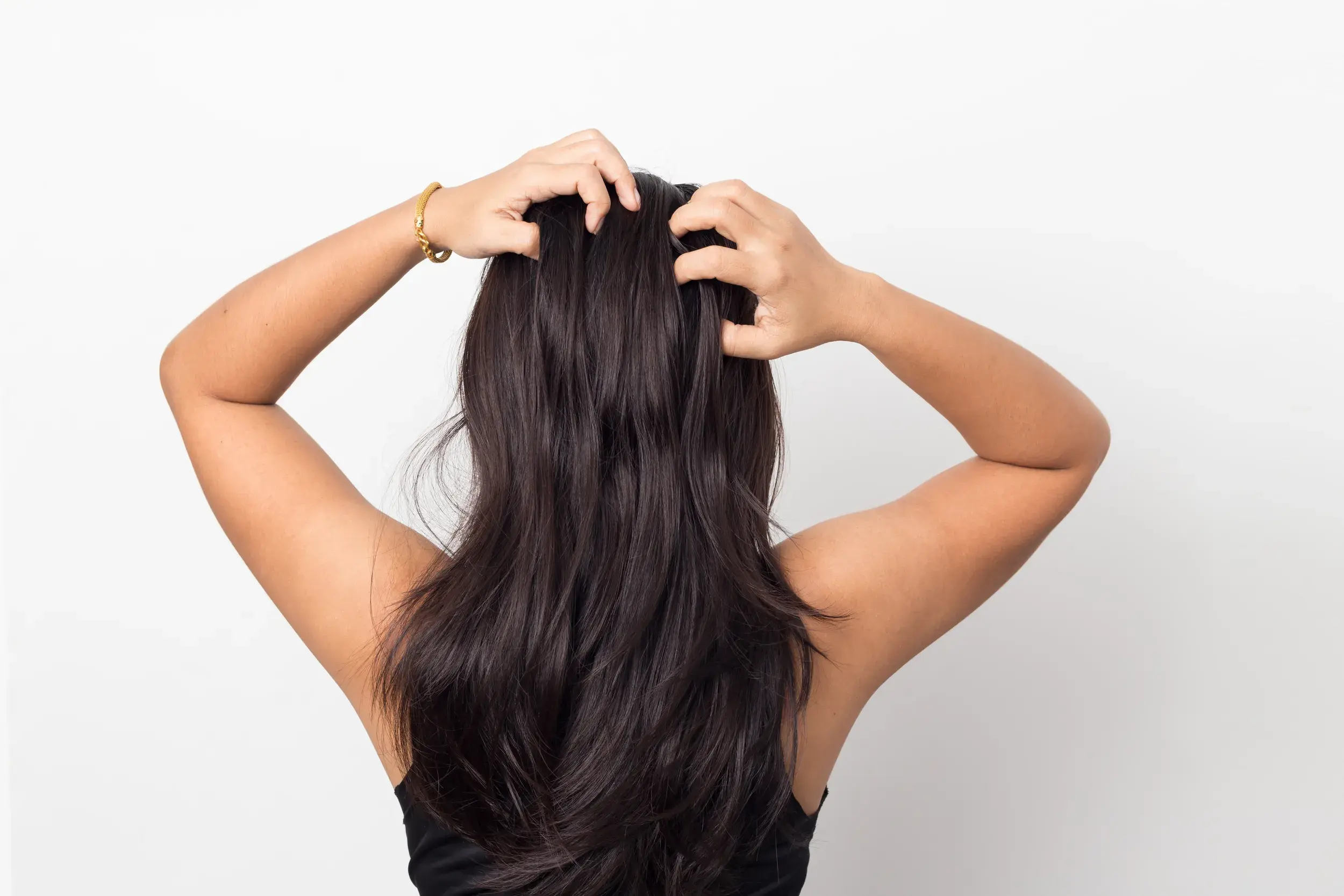 back of a woman in black tank top with hands through her long black hair