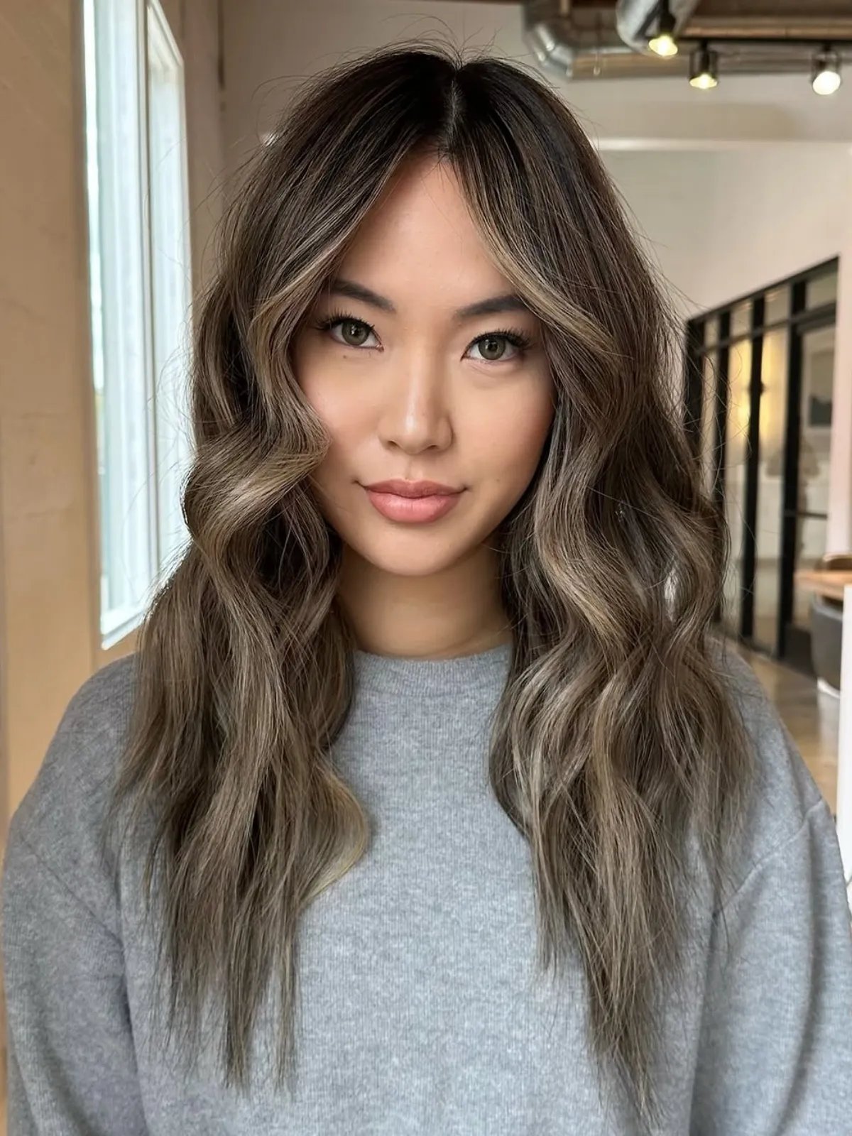 Model with brown hair featuring dark ashy blonde highlights.