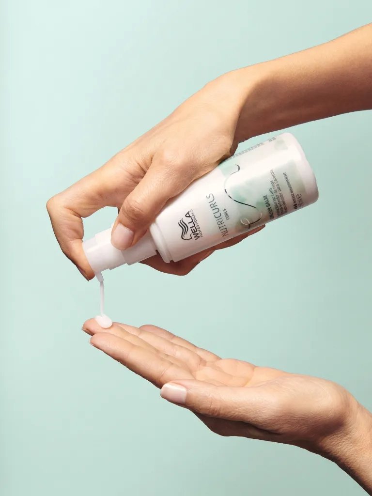 Model pumps NutriCurls Curlixir Balm into palm of hand.