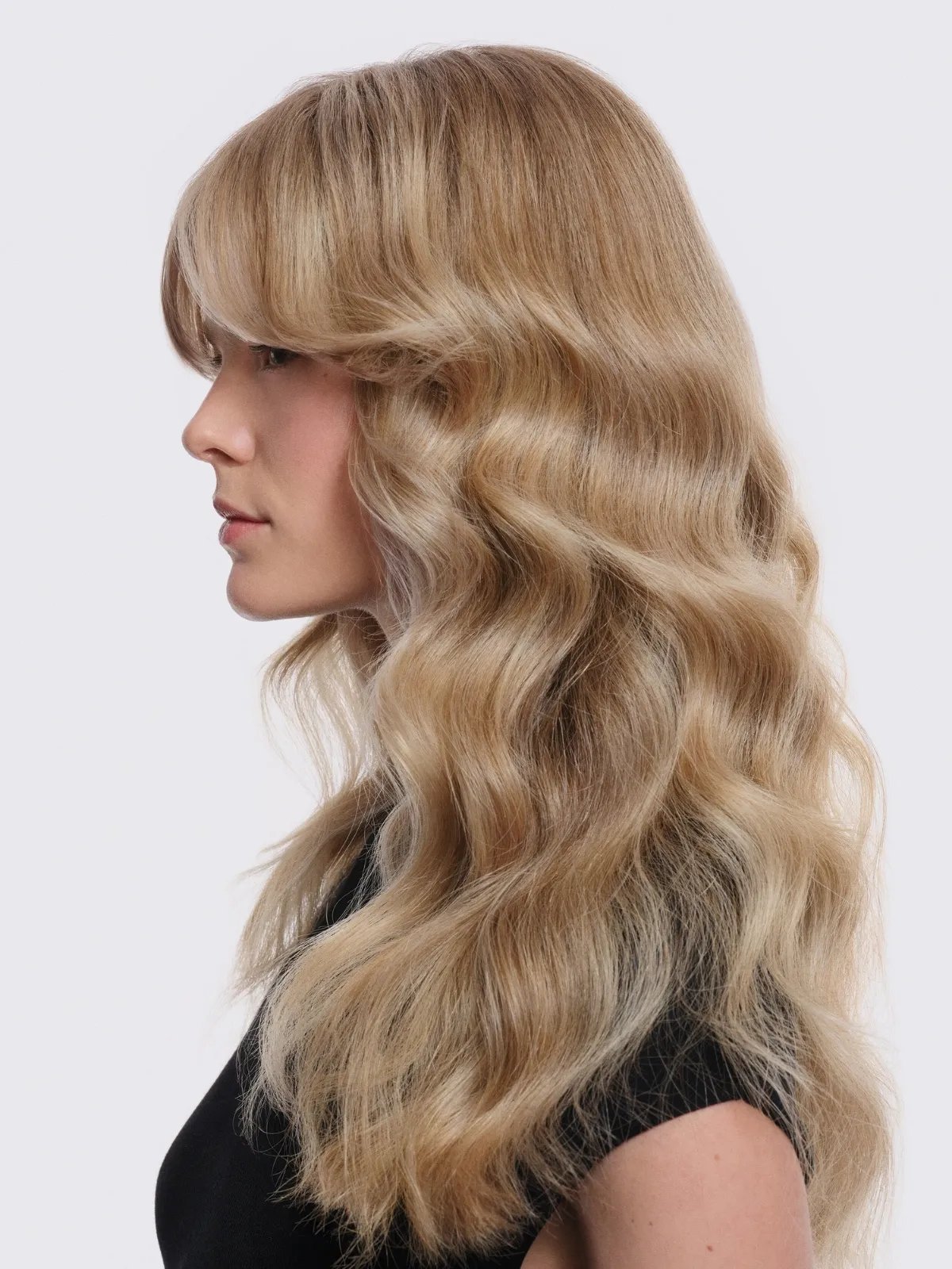 Model with bright, wavy, cashew blonde hair after a Supernatural Color service.