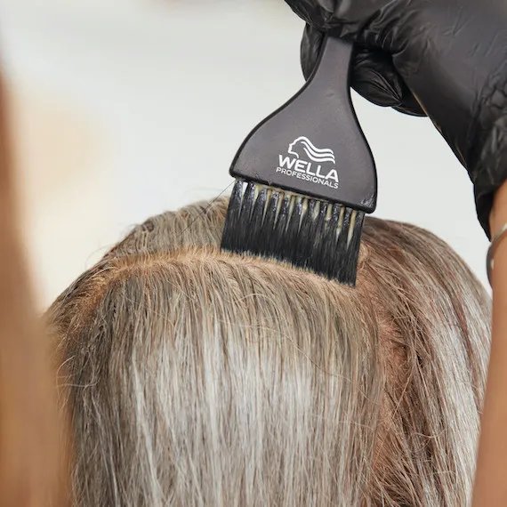 Close-up of Wella hair color being applied to gray roots.