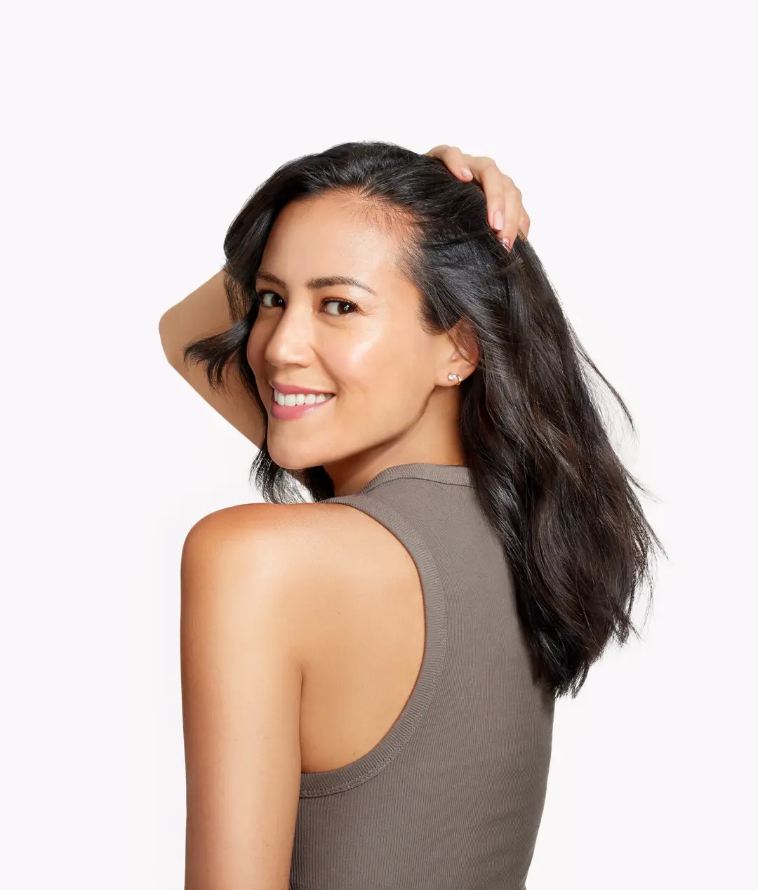 Brunette woman turned to the side smiling at camera with hand on hair