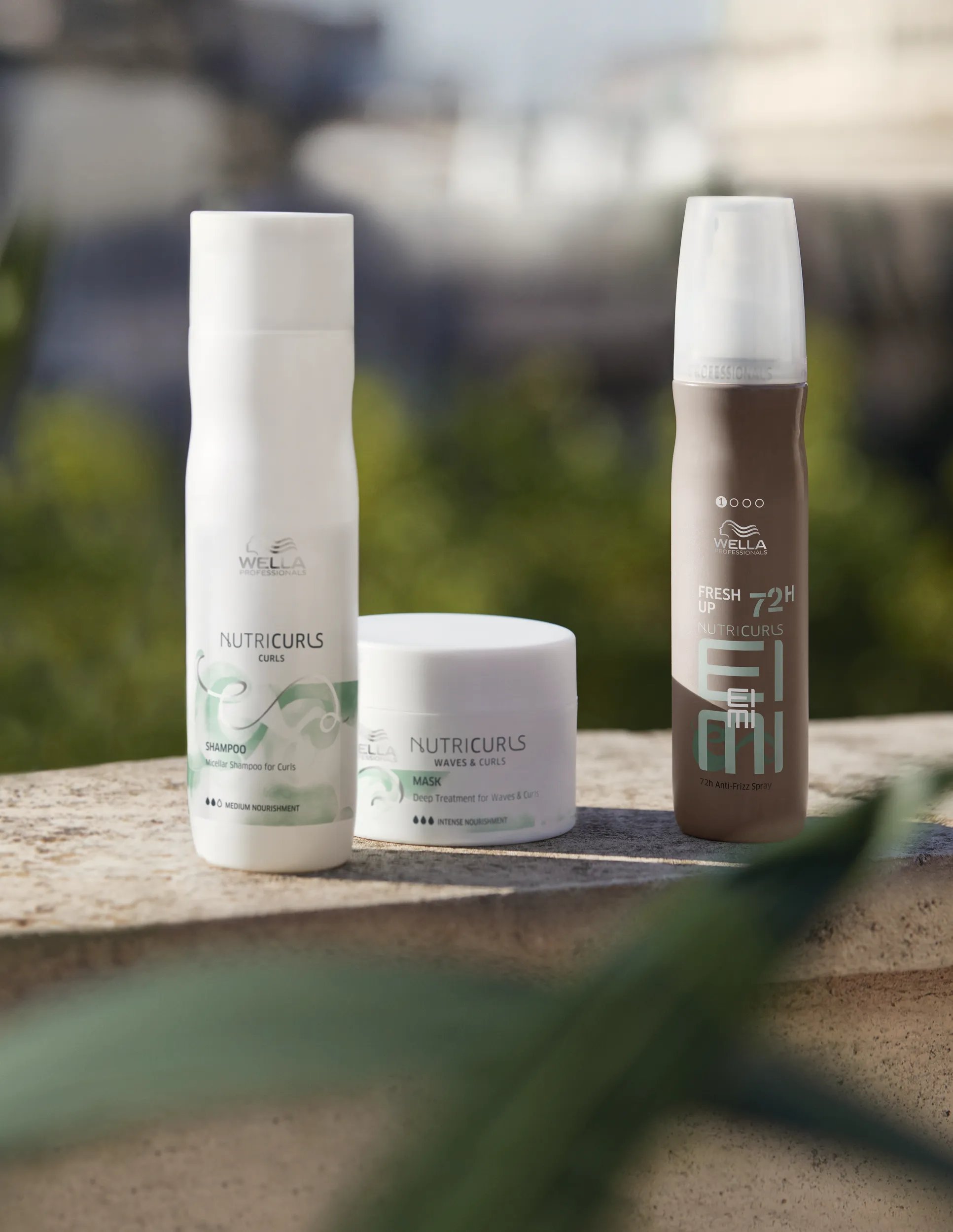 NutriCurls Shampoo, Mask and Fresh Up spray on a concrete surface.