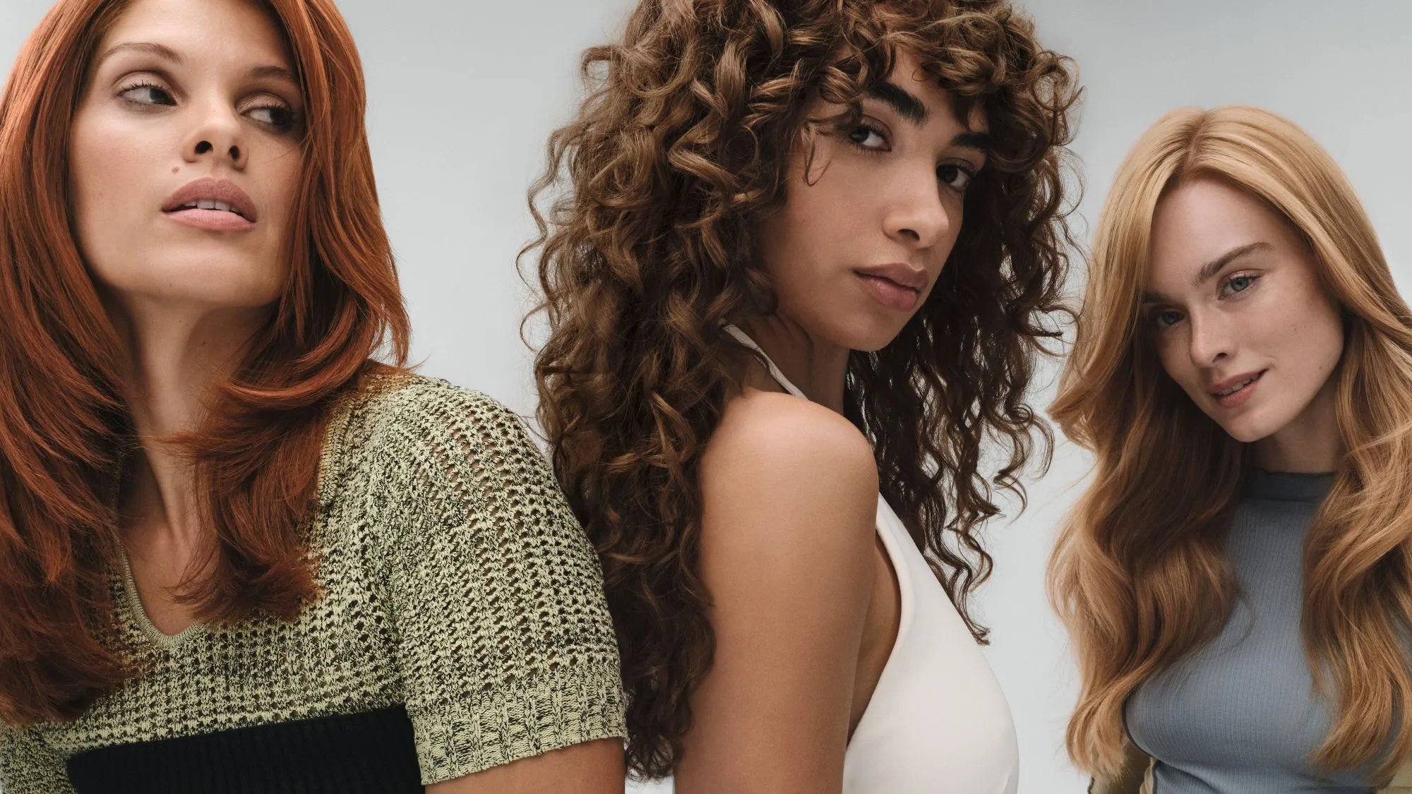 Three models: one with copper red hair, one with chocolate brown curls, and one with a blonde blow-dry.