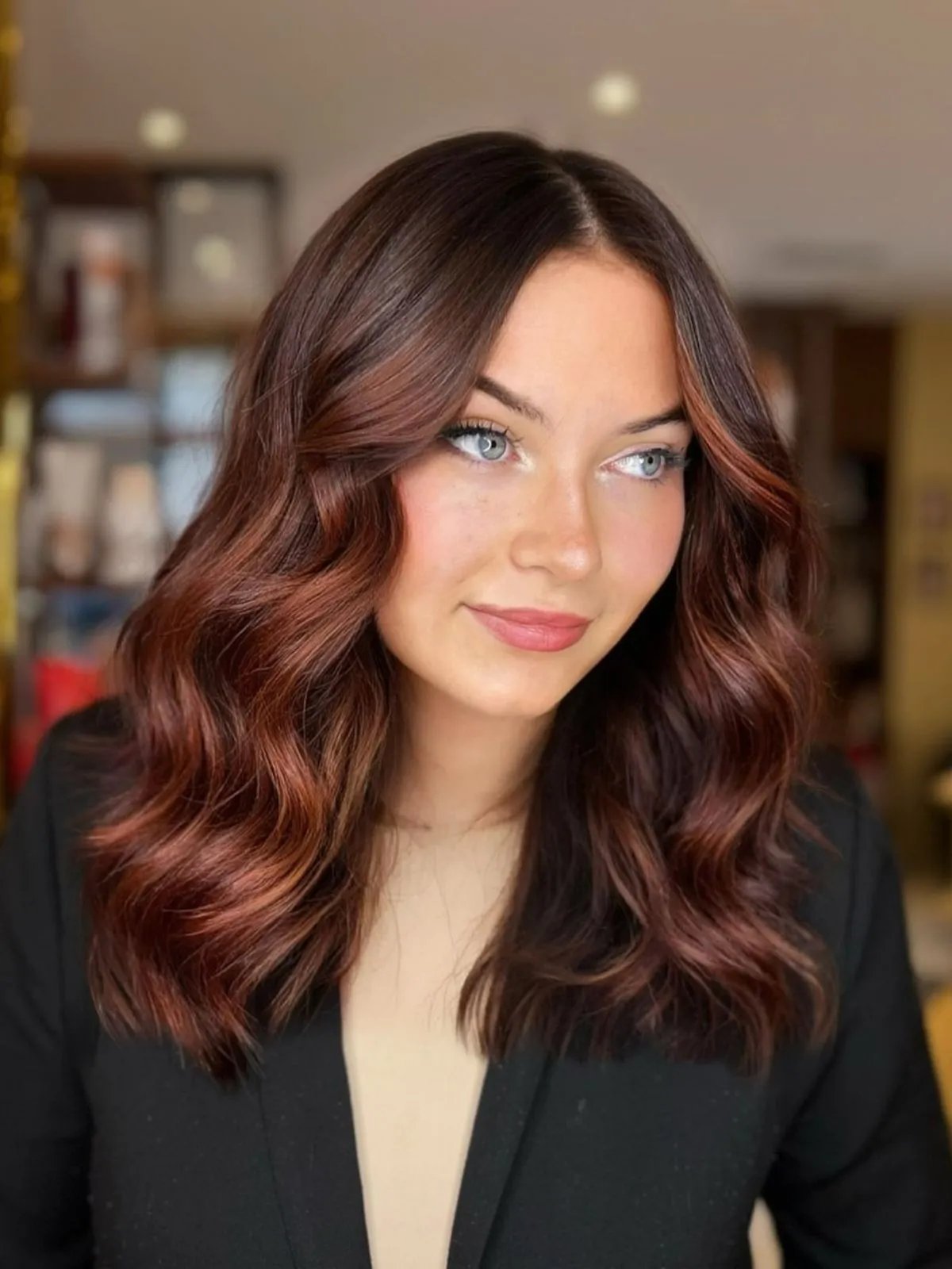 Model with dark brown hair featuring dark, warm-toned red balayage.