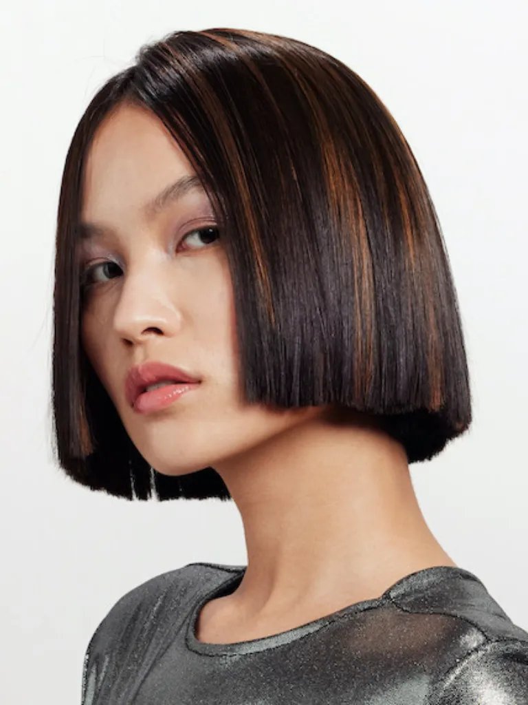 Model with dark brown, ultra-short bob haircut featuring caramel highlights.