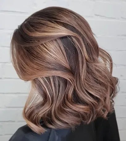 Model with short, wavy hair and dark brown balayage, created using Wella Professionals. 