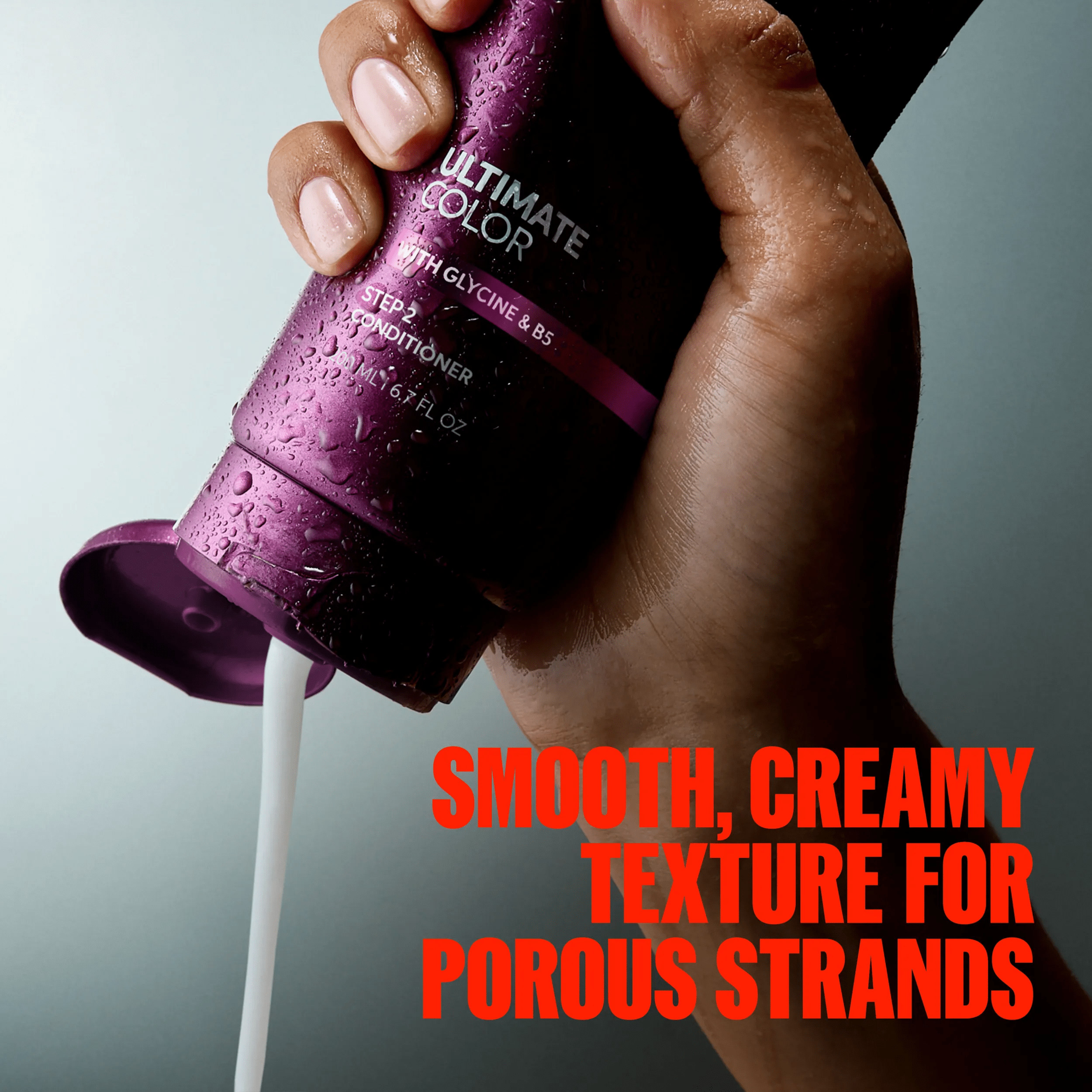Imagem da mão da modelo a apertar um frasco do condicionador Ultimate Color. A sobreposição de texto diz: "Textura suave e cremosa para cabelos porosos".