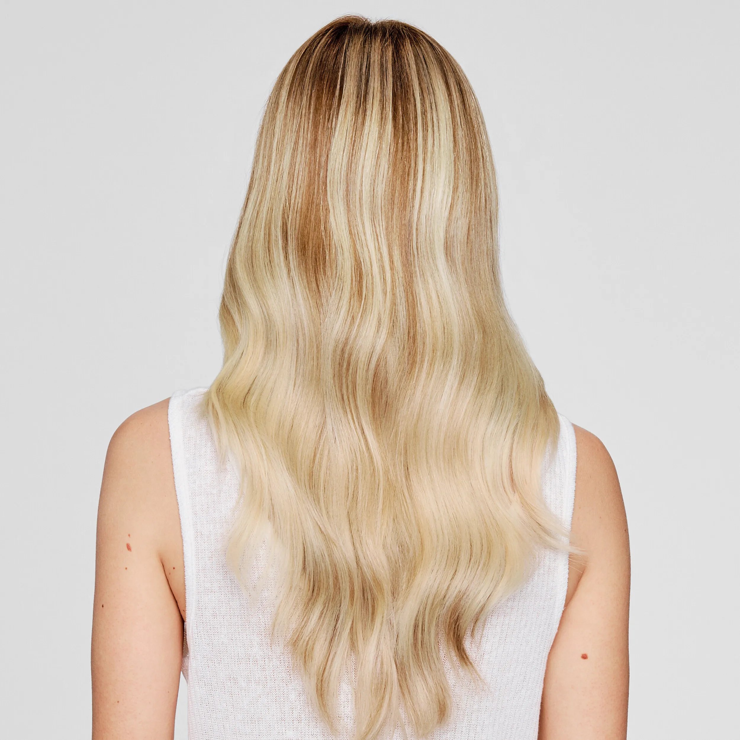 Back view of a model against a light gray background. The model's hair is blonde and smooth, they are wearing all white. 