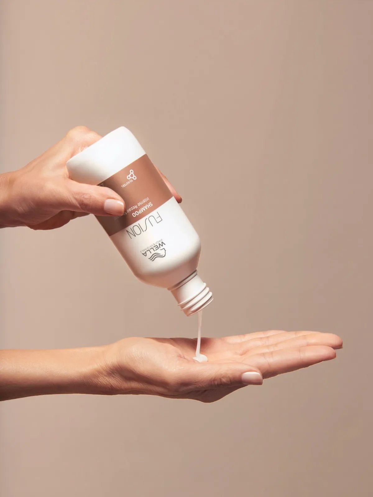Model pours Fusion Intense Repair Shampoo into palm of hand.