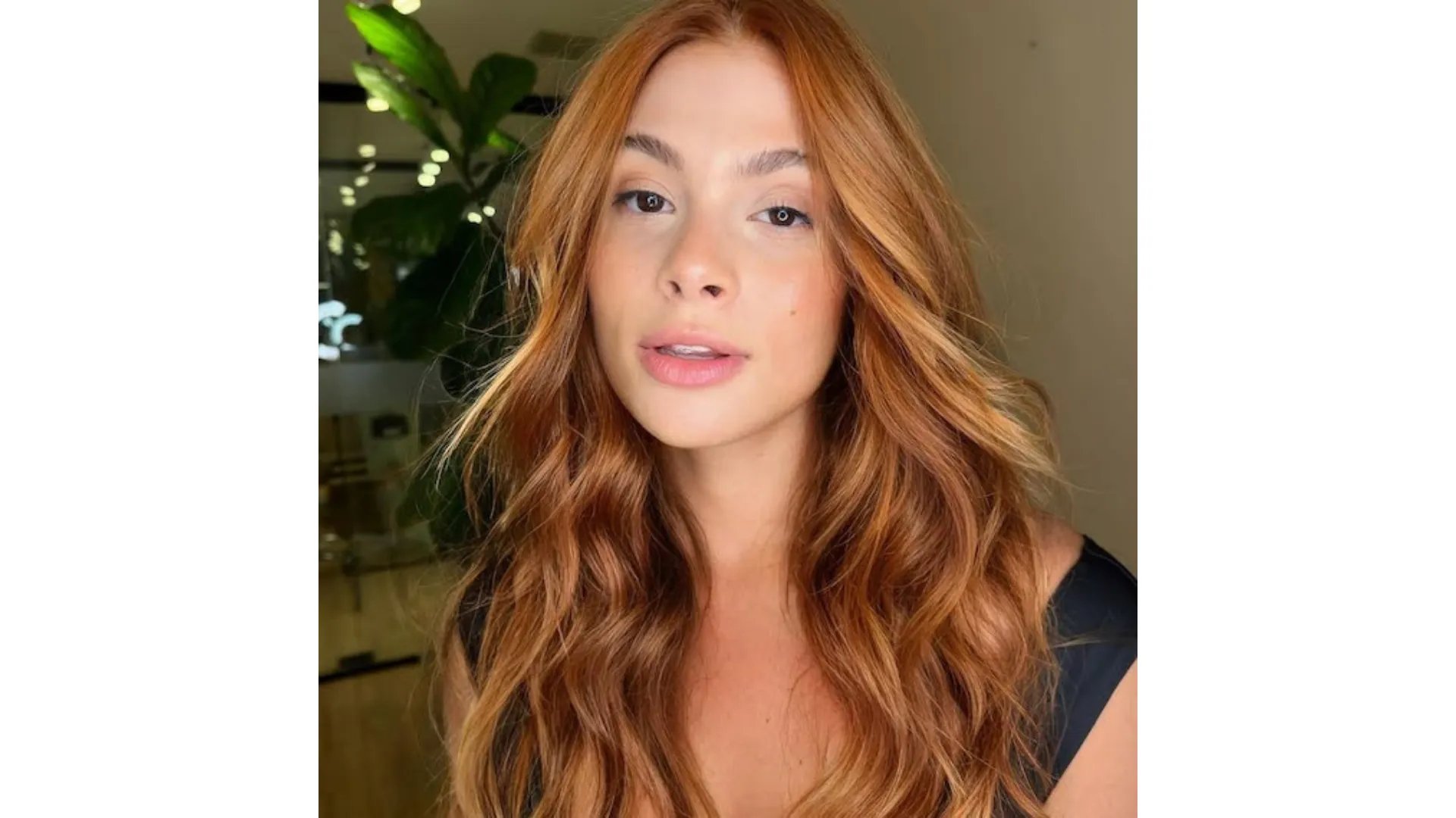 Model with warm, peachy, copper-colored hair styled in tousled waves.