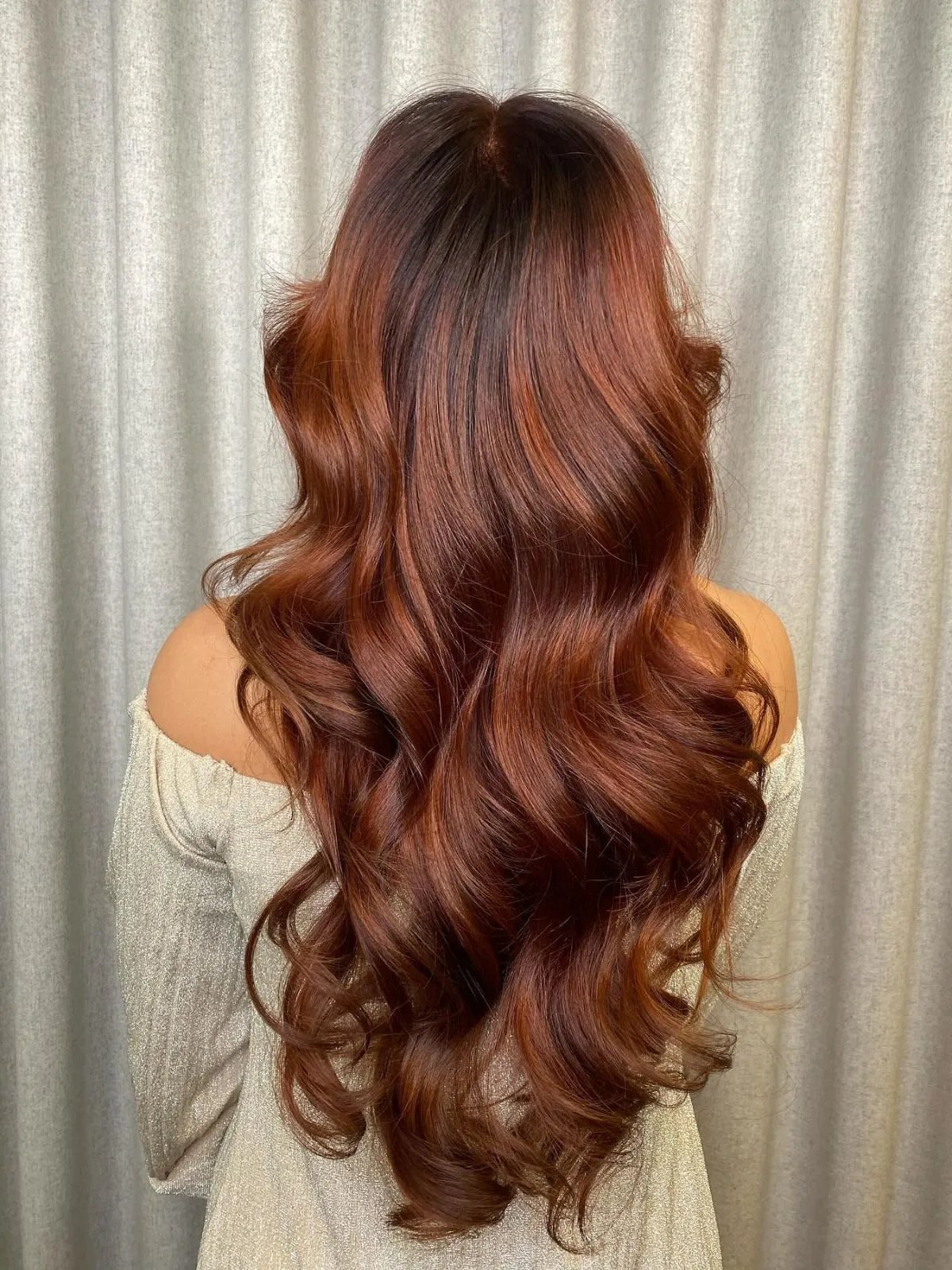 Model with long, loosely curled, copper auburn hair.