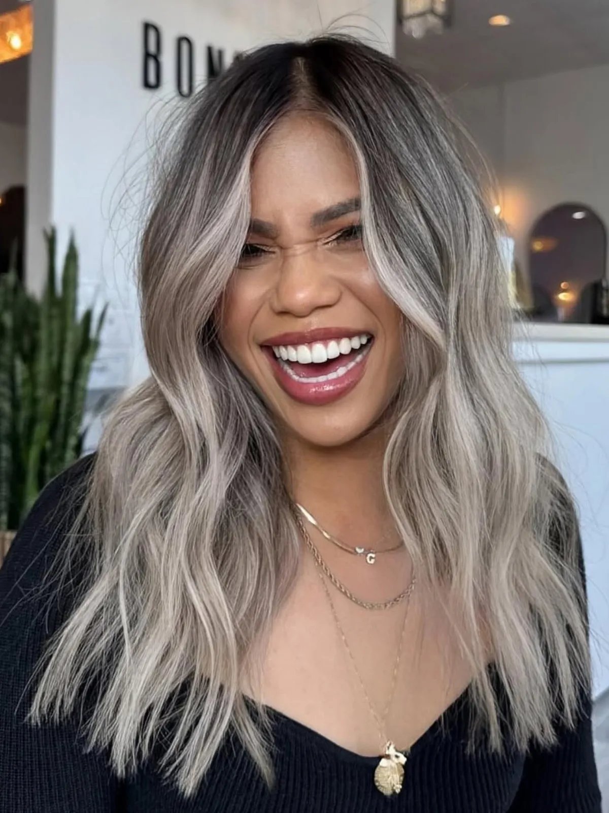 Model with wavy, silver hair featuring a dark shadow root.