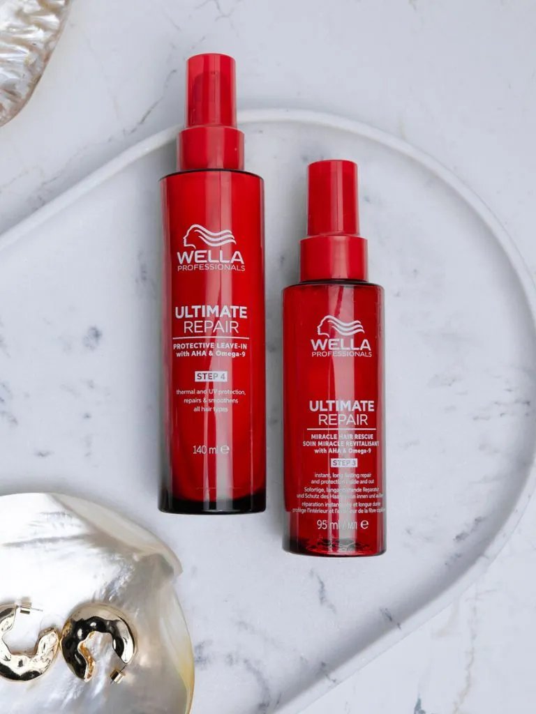 Two bottles of ULTIMATE REPAIR Protective Leave-In on a marble surface.