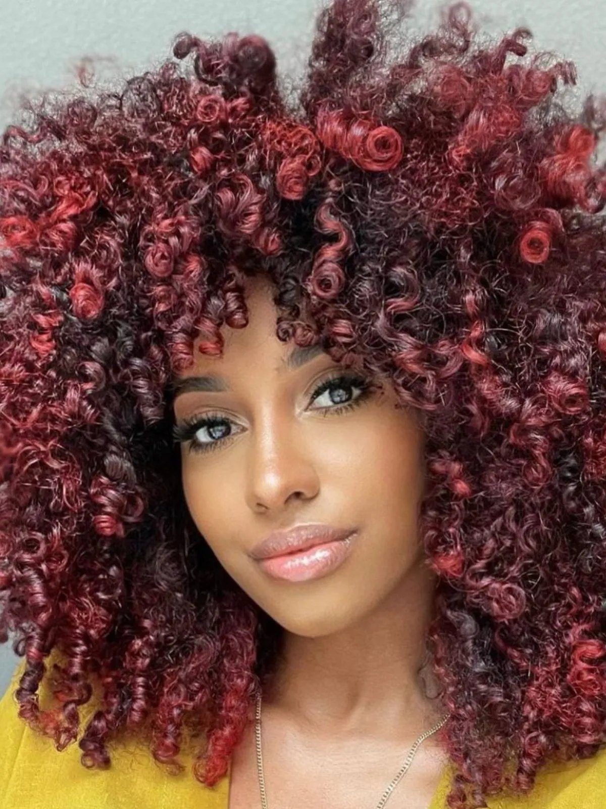 Model with dark curls featuring bright, cherry red highlights.