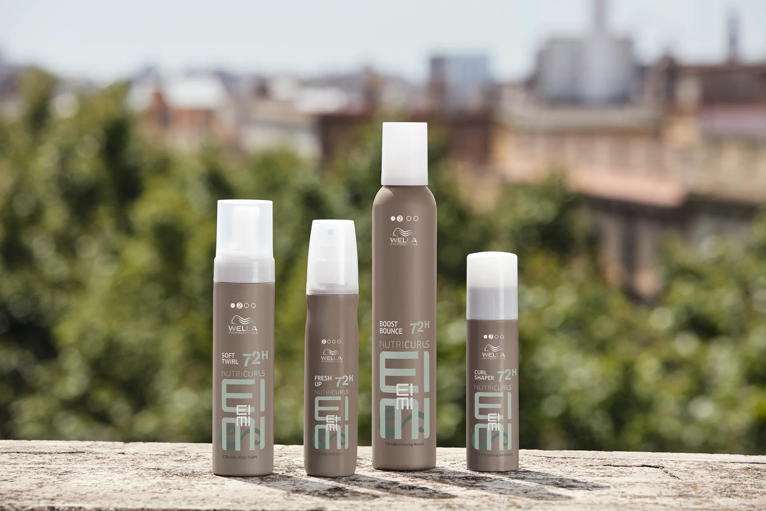 Collection of Wella EIMI styling products lined up on a stone surface.