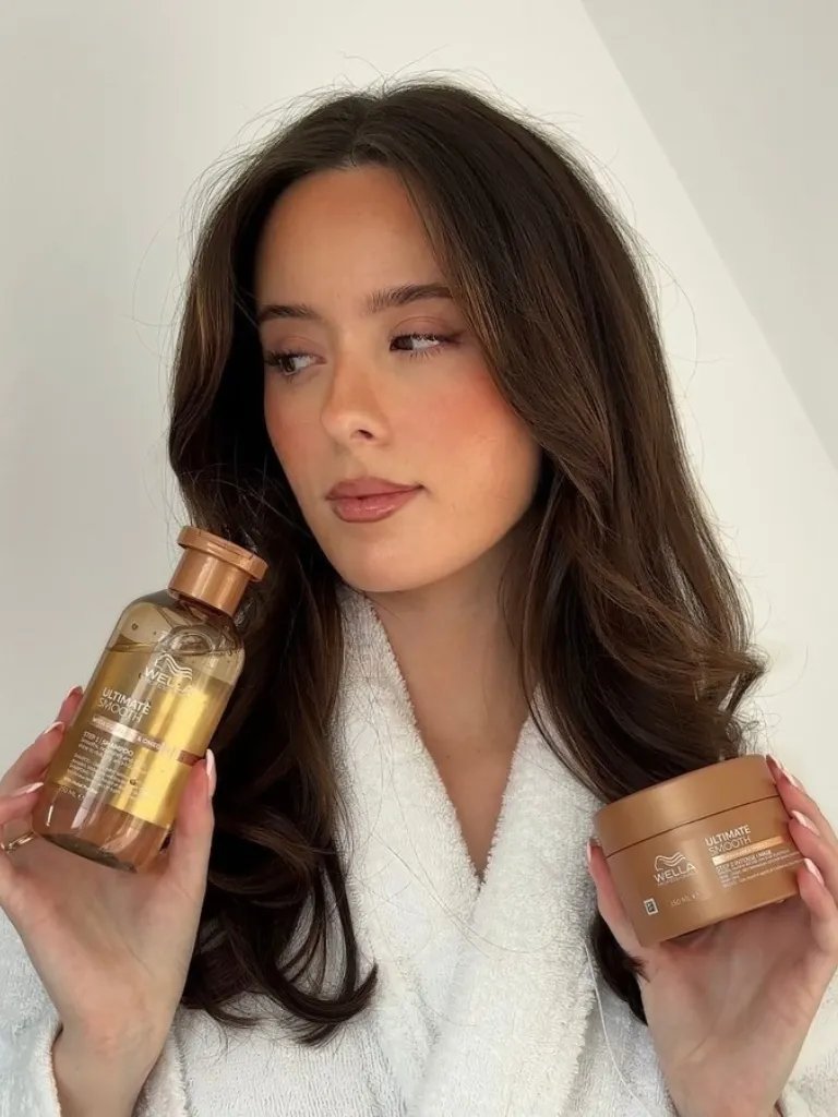 Model with long, brown hair holding ULTIMATE SMOOTH Shampoo and ULTIMATE SMOOTH Mask.