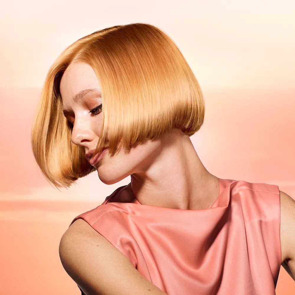 Side profile of model with ultra-glossy, glassy, apricot blonde hair.