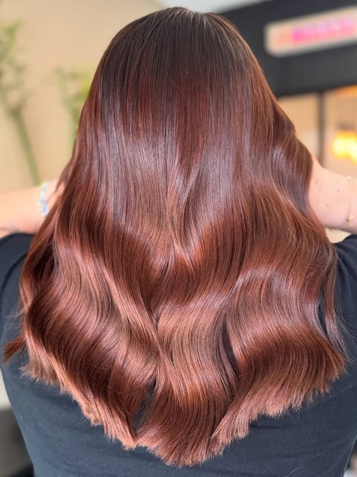 Back of model’s head with loosely tousled hair that’s maroon at the roots and mauve through the lengths.