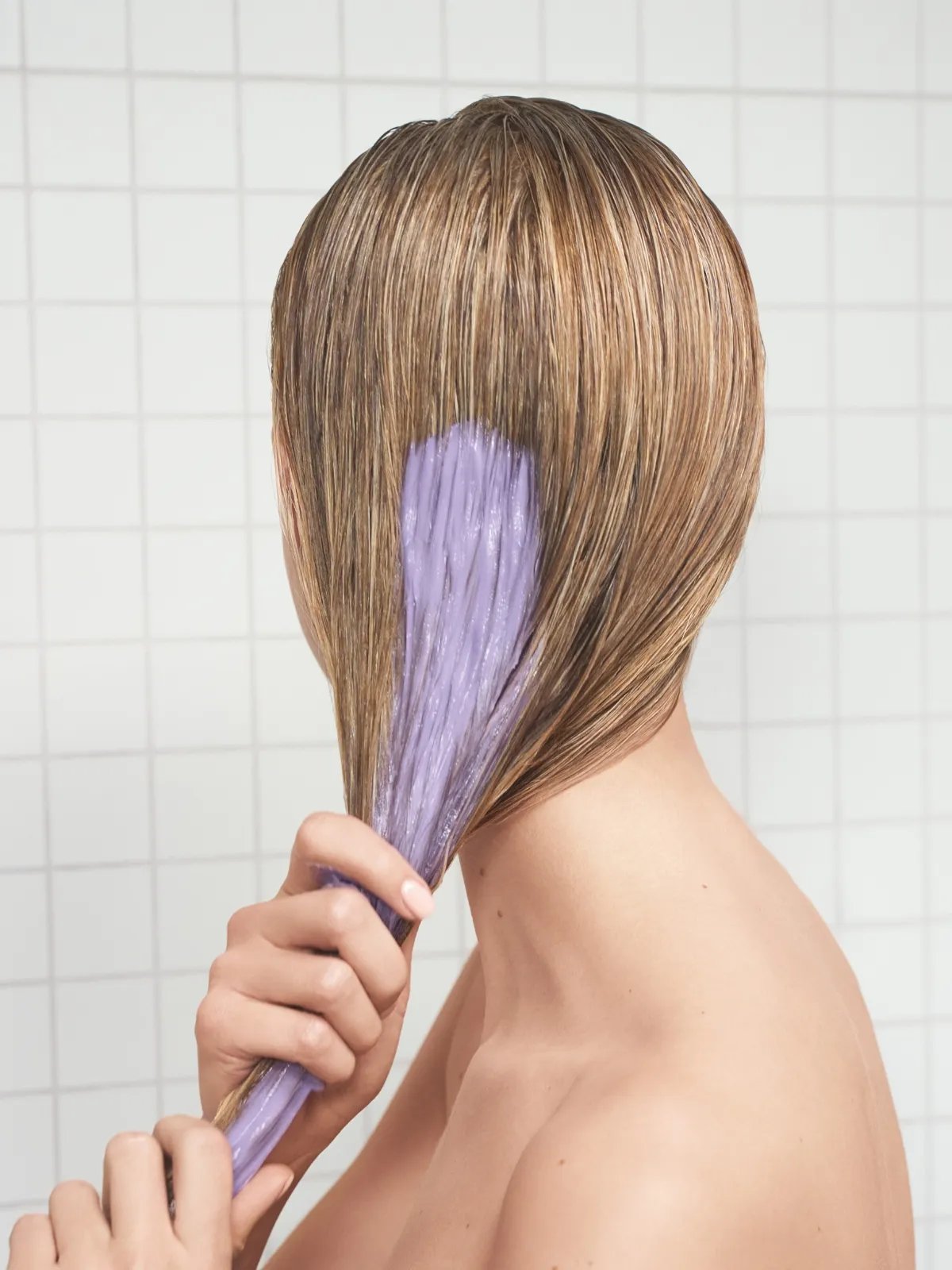 Model smooths ULTIMATE COLOR BLONDE Conditioner through damp hair.