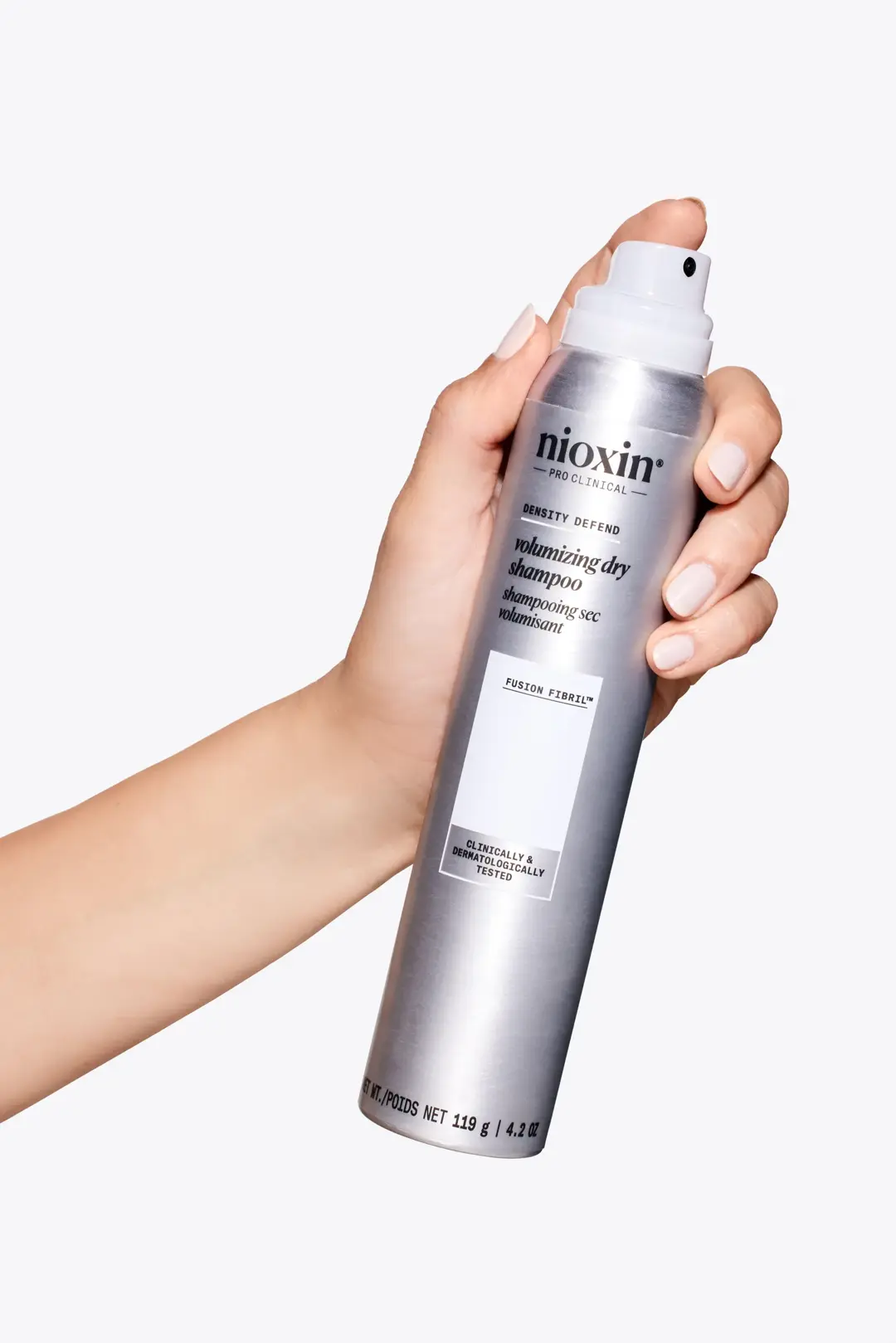 Nioxin Volumising Dry Shampoo tenuto da una mano su sfondo bianco