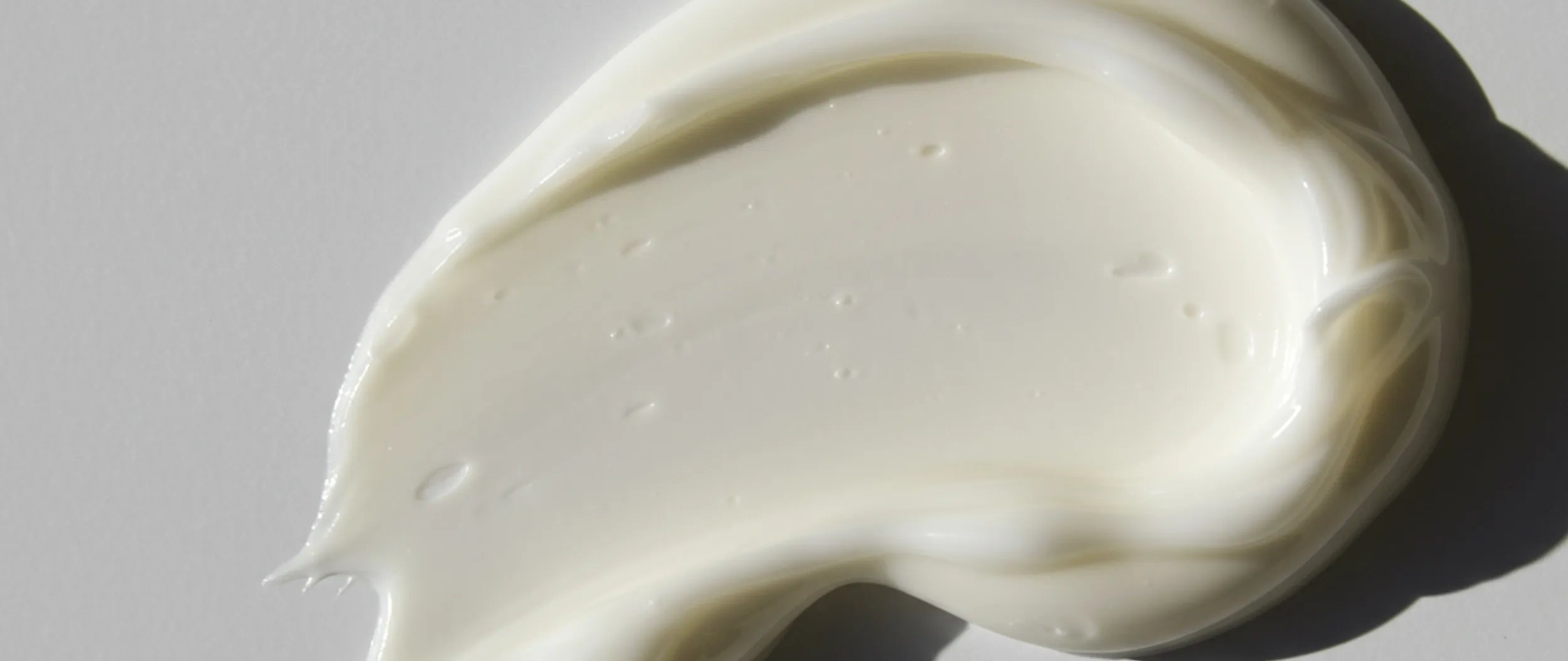 Swirl of white cream against a light-colored background.