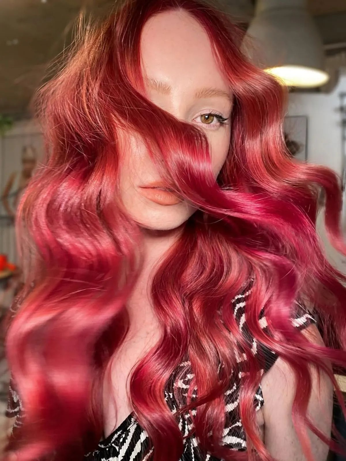 Model with long, ruby red hair styled in beachy waves. 