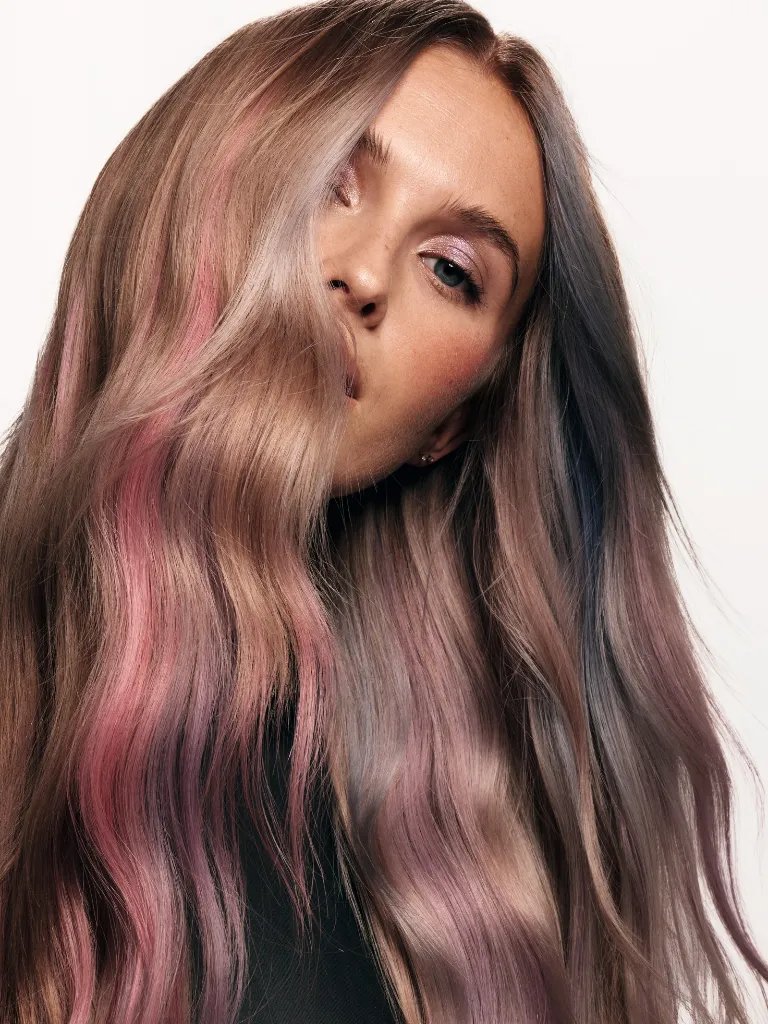 Model with dark blonde hair featuring strokes of pastel pink, blue and purple tones.
