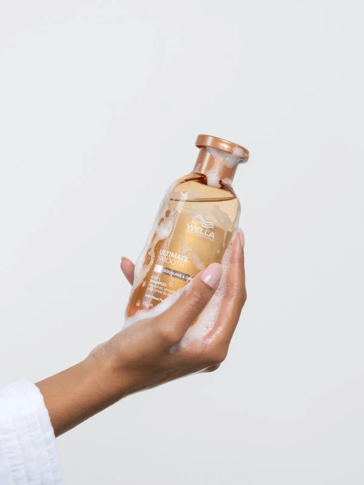 ULTIMATE SMOOTH Shampoo in model’s hand.