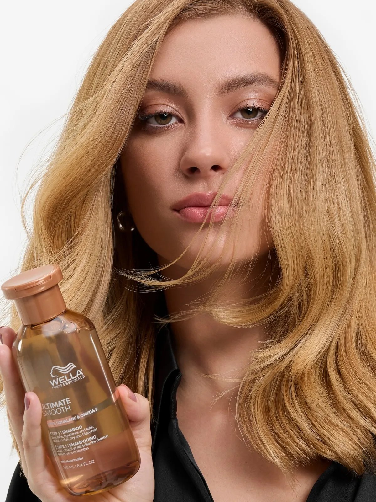 Model with smooth blonde hair holds up ULTIMATE SMOOTH Shampoo.