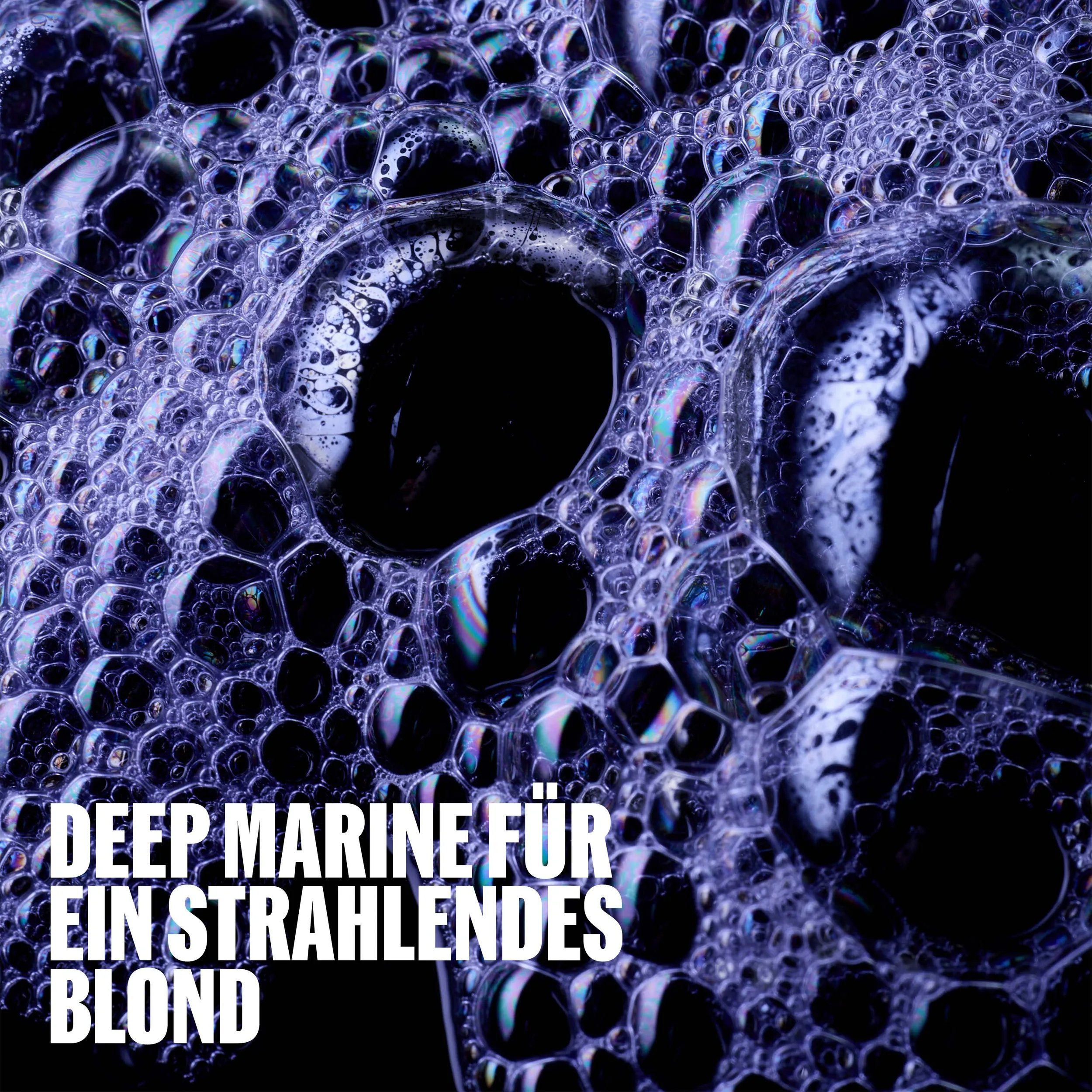 Close-up image of soapy bubbles against a deep purple background. Text overlay states "Deep Marine For A Radiant Blonde"