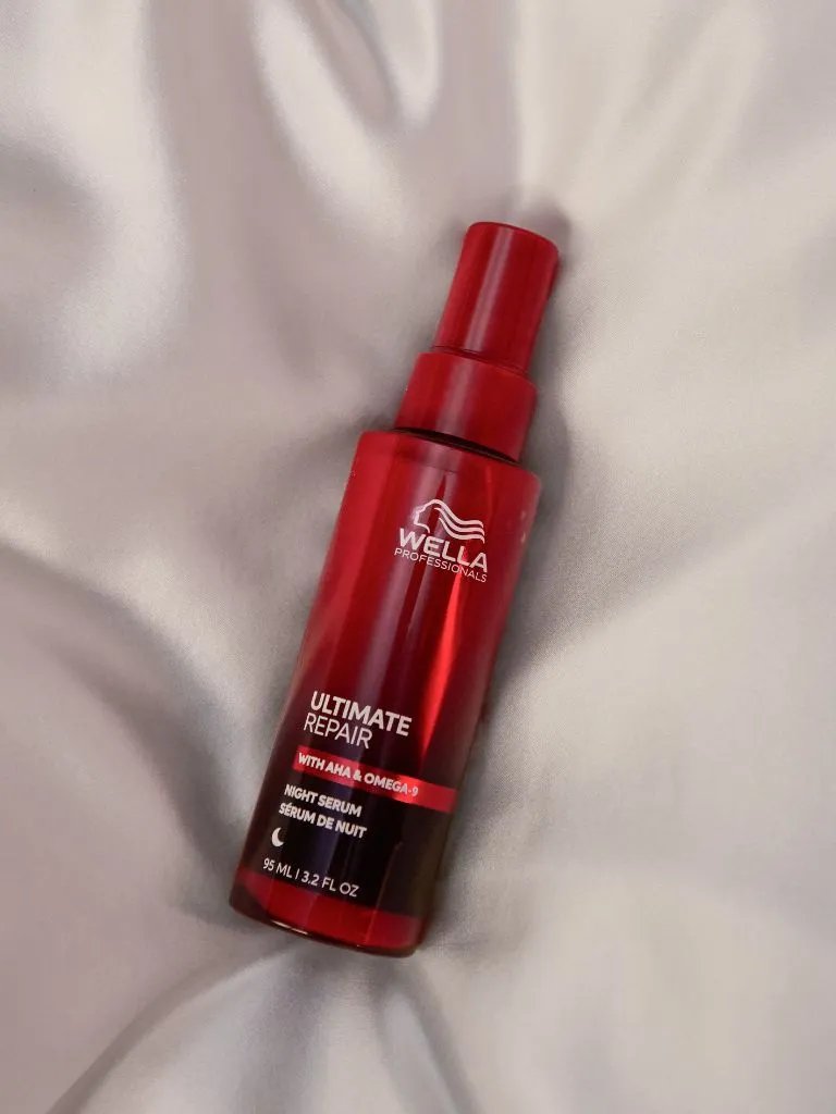 ULTIMATE REPAIR Night Serum bottle on silk sheets.