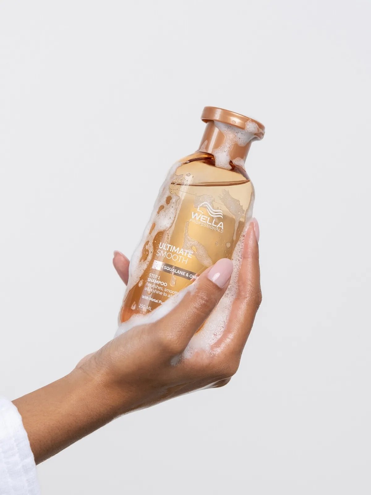 Model holding bottle of ULTIMATE SMOOTH Shampoo