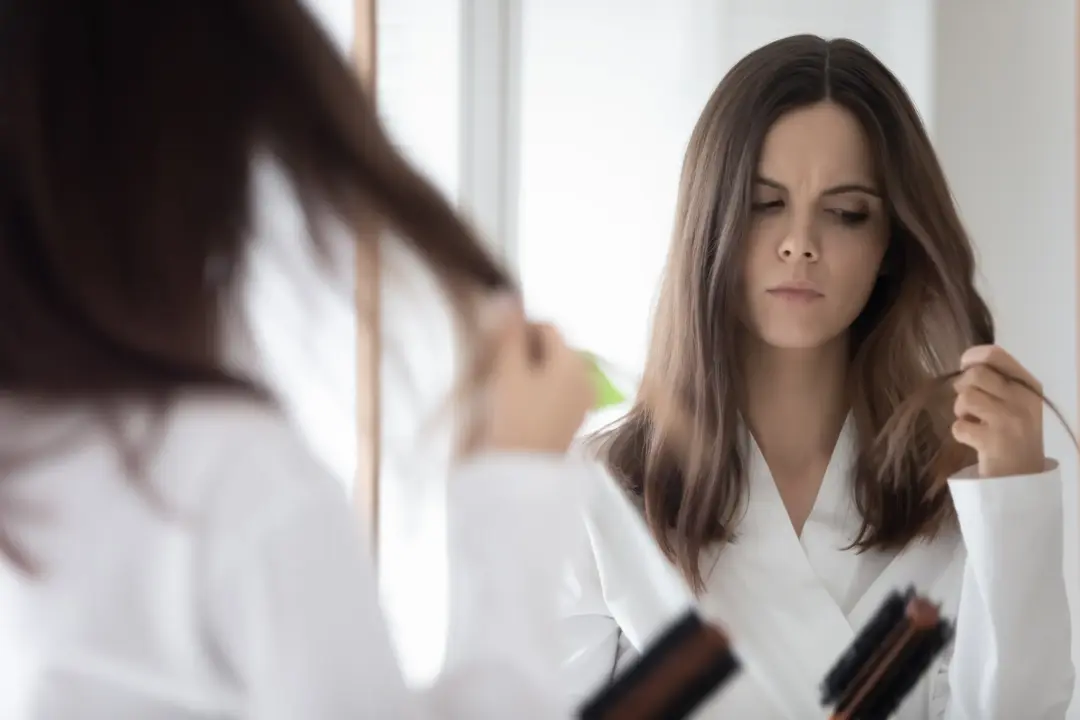 brunette woman mirror reflection looking at the ends of her hair