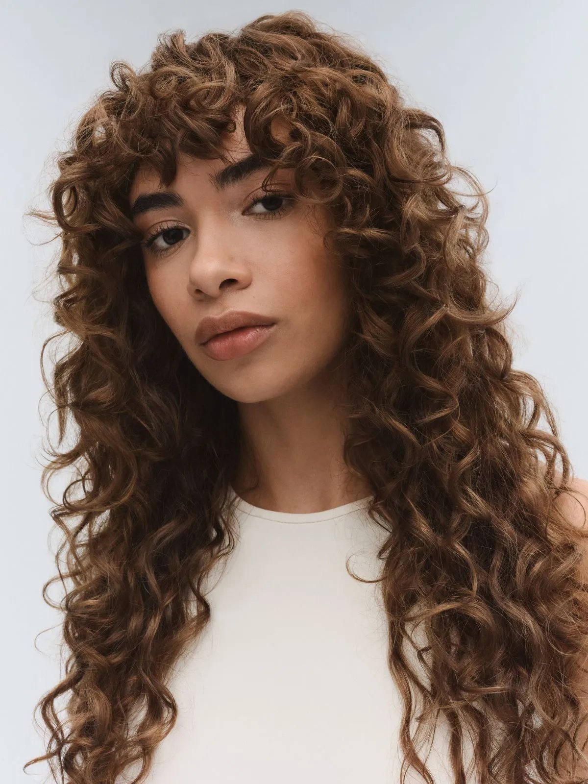 Model with long, curly, chocolate brown hair.