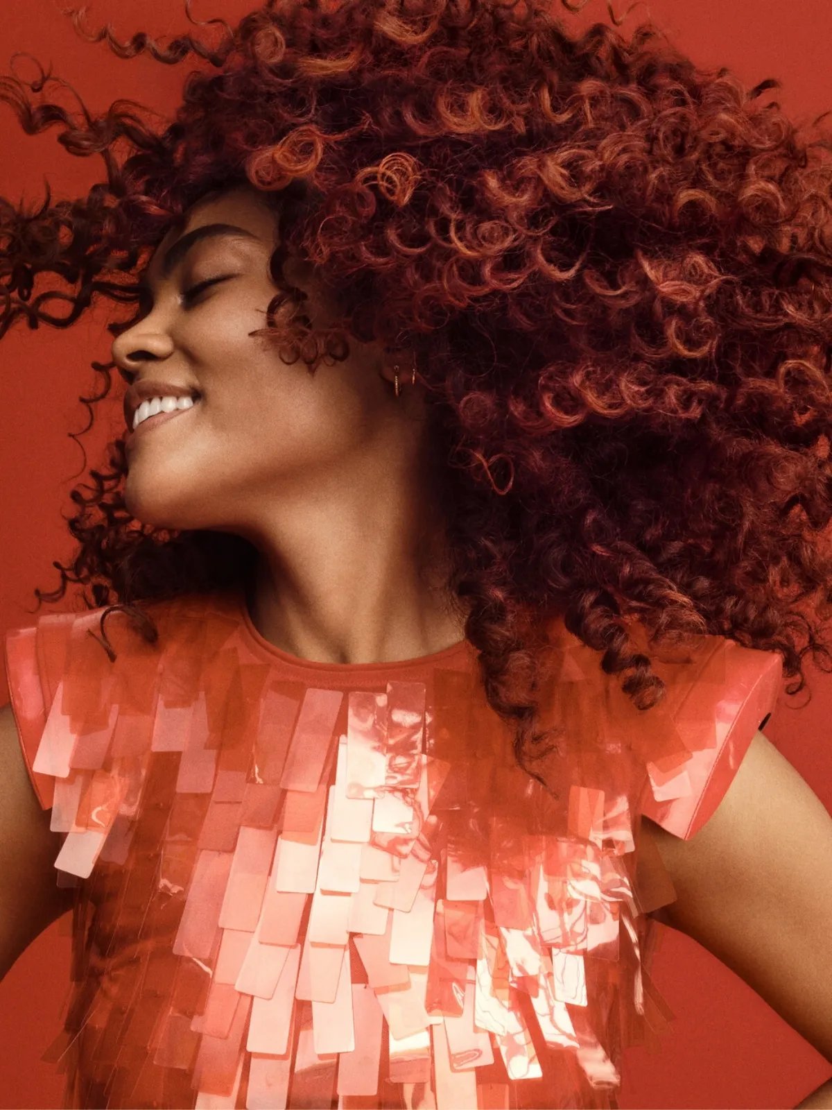 Model swishes their healthy, curly, copper-brown hair from side to side.