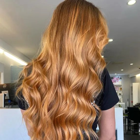 Model with ultra-long, golden copper brown hair styled in undone waves