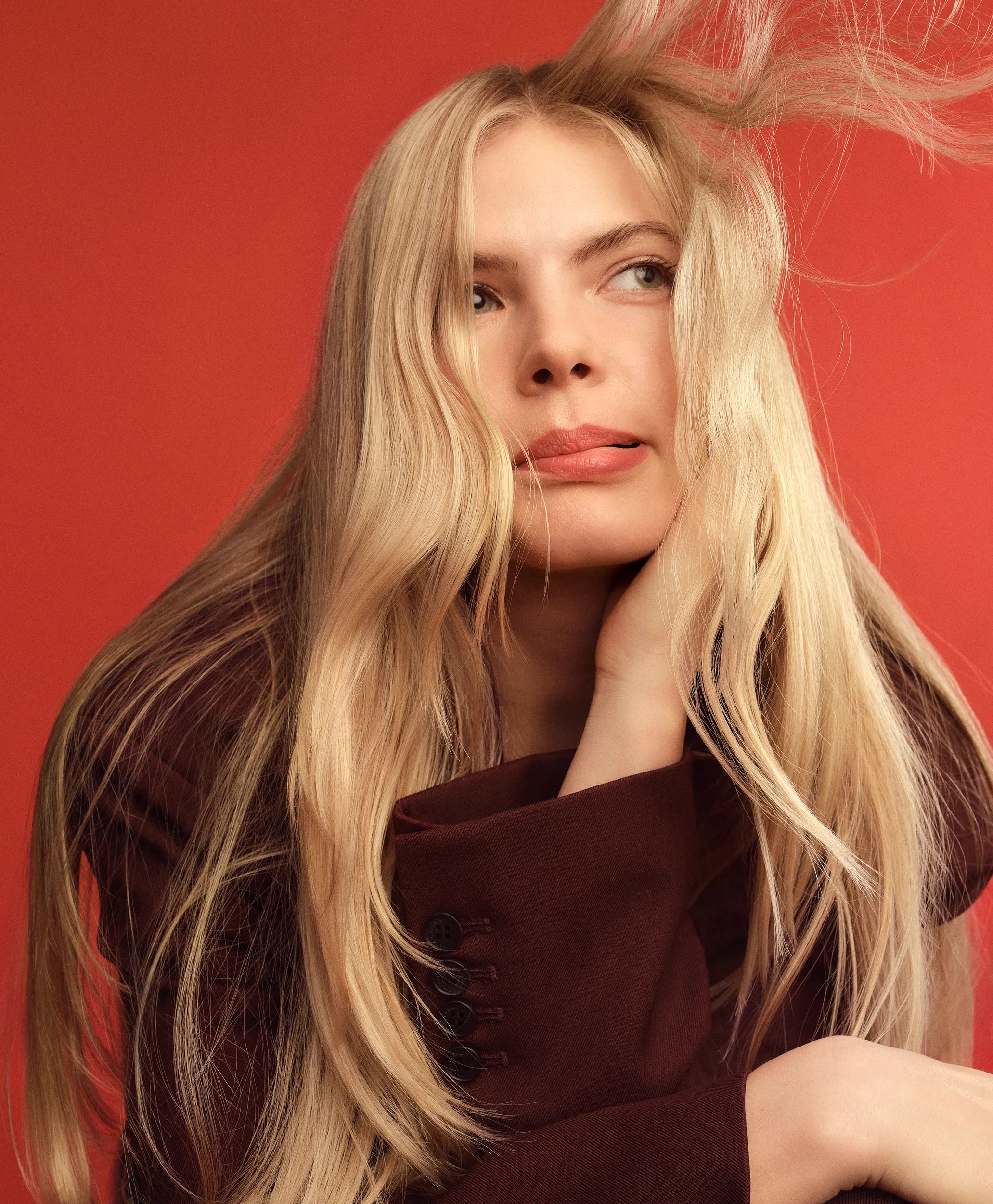 Model with sandy blonde, wavy hair and a fringe faces the camera.