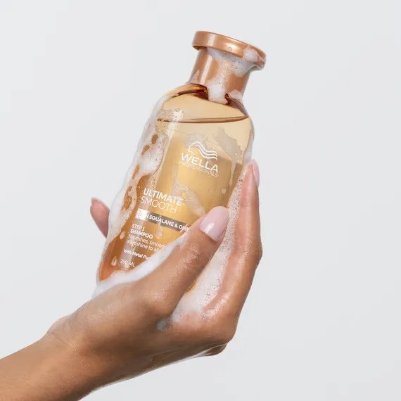 Model holds bottle of Ultimate Smooth Shampoo