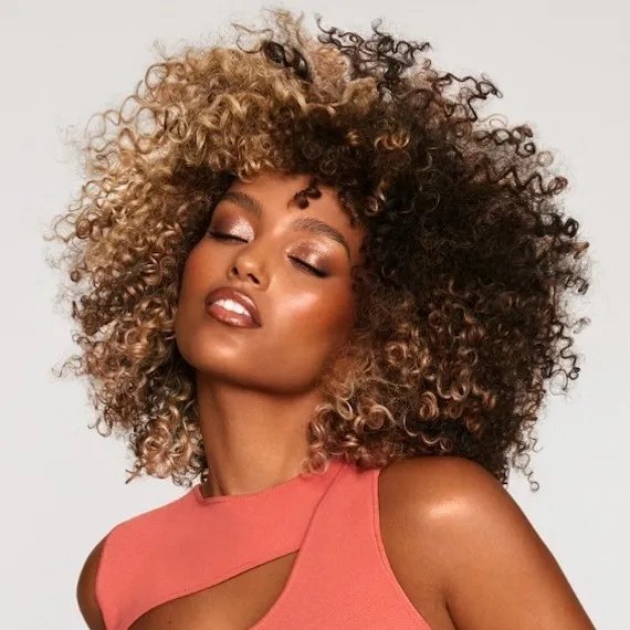 Model with brown curly hair with blonde highlights