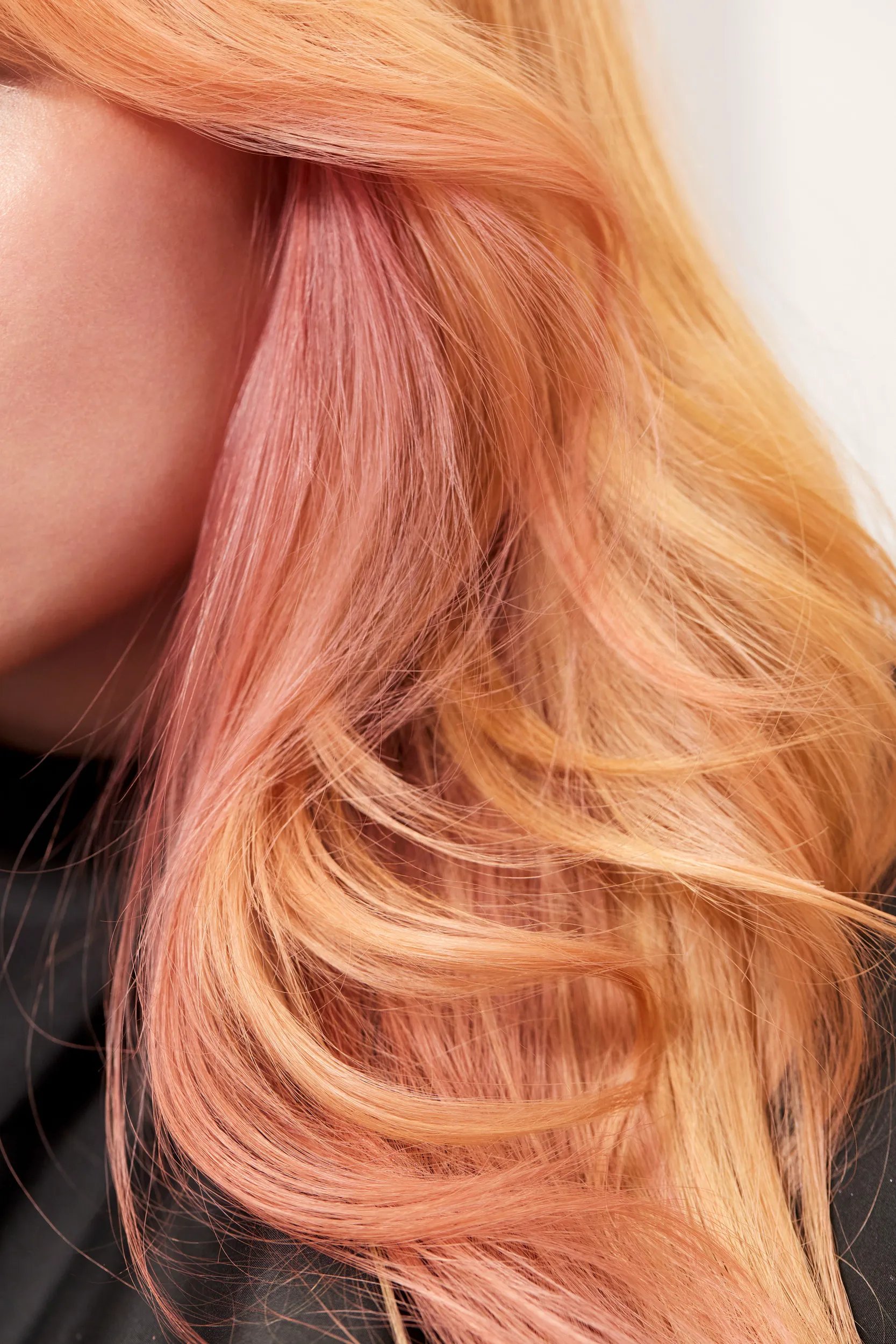 Woman with long, rich copper hair in soft waves under golden hour lighting, showcasing Wella Professionals Golden Hour initiative.
