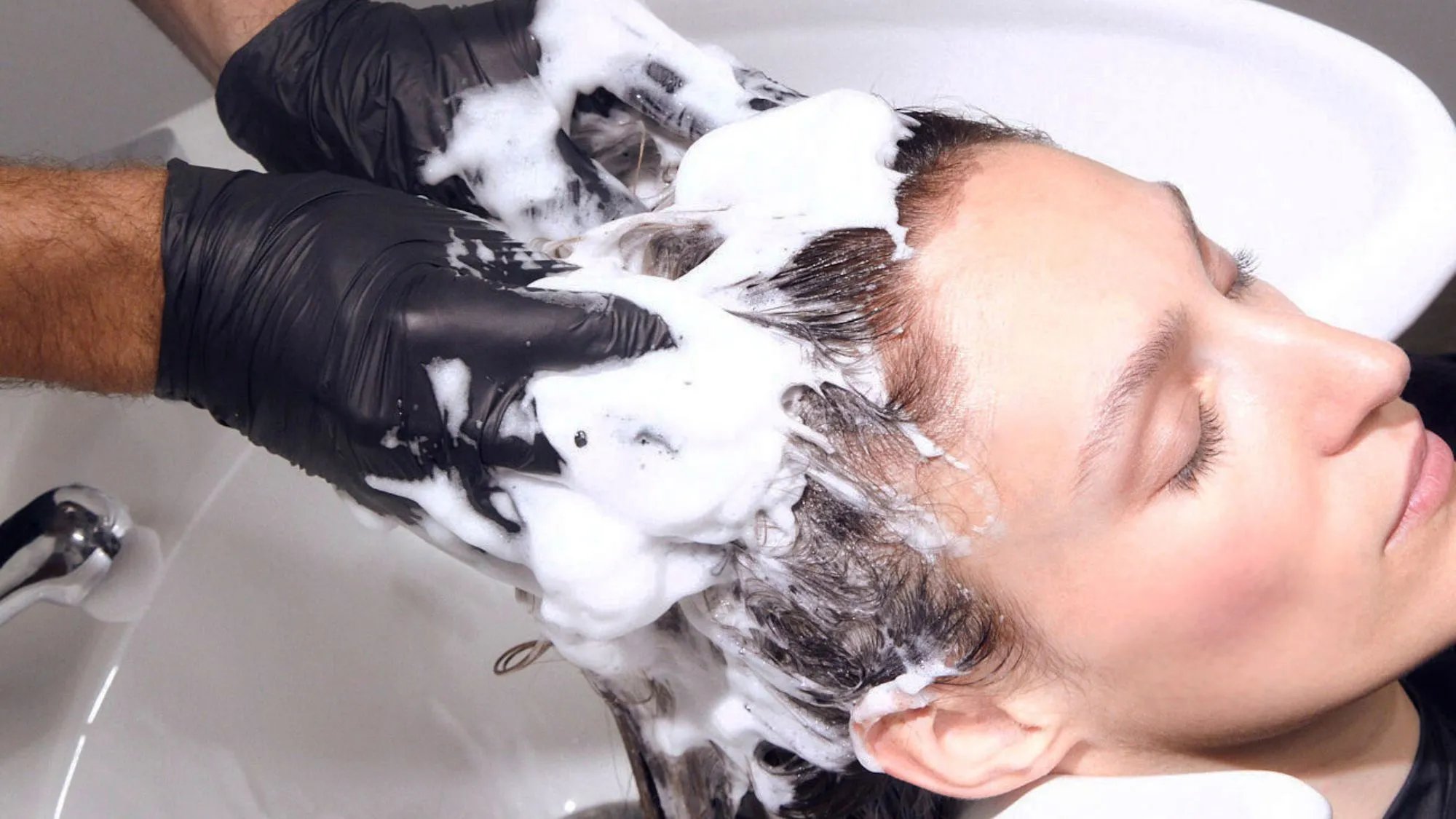 Model has shampoo massaged into hair by a stylist.